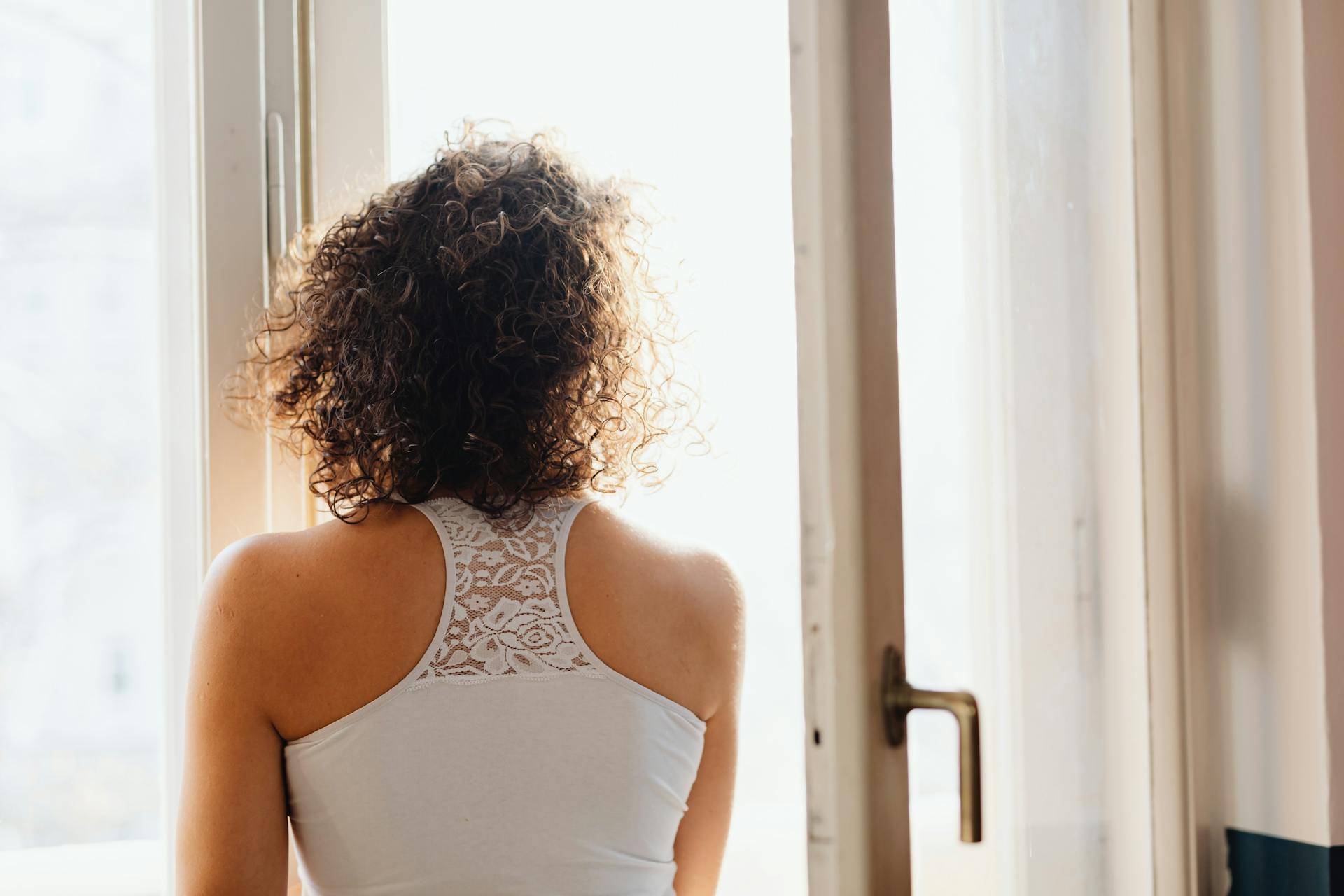 Woman standing near window with her eyes closed | Source: Pexels