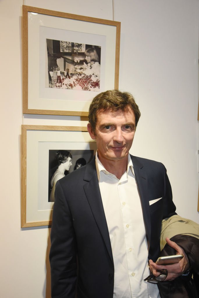 Denis Westhoff pose avec un portrait de sa mère écrivain Françoise Sagan (ci-dessus) pendant l'exposition "La Femme dans Le Siecle" et le cocktail de remise des prix à la Galerie FRM le 14 novembre 2017 à Paris, France. | Photo : Getty Images Denis Westhoff pose avec un portrait de sa mère écrivain Françoise Sagan (ci-dessus) pendant l'exposition "La Femme dans Le Siecle" et le cocktail de remise des prix à la Galerie FRM le 14 novembre 2017 à Paris, France. | Photo : Getty Images