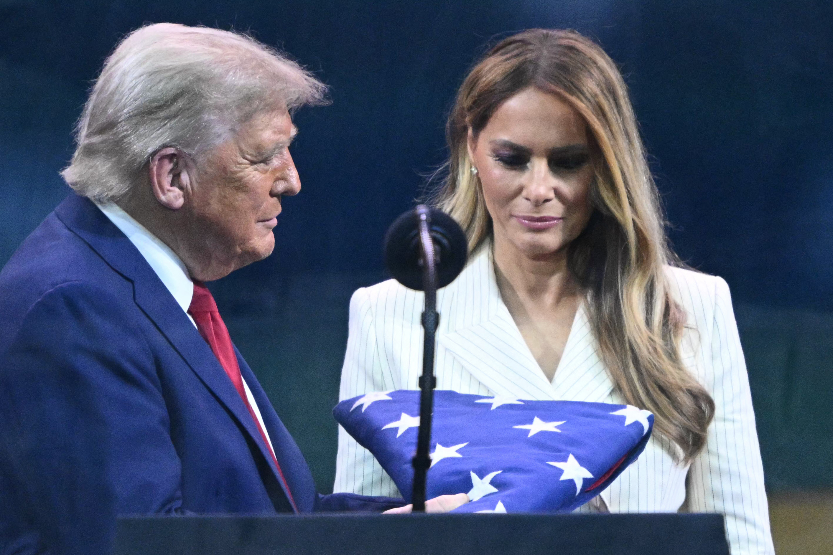 Donald and Melania Trump look at a folded U.S. flag presented to Donald by a member of the Army’s Golden Knights during the closing moments of the 250th Army anniversary parade, on June 14, 2025.