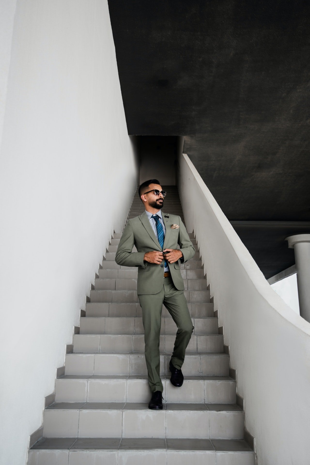 A man in grey suit standing on a staircase | Photo: Pexels