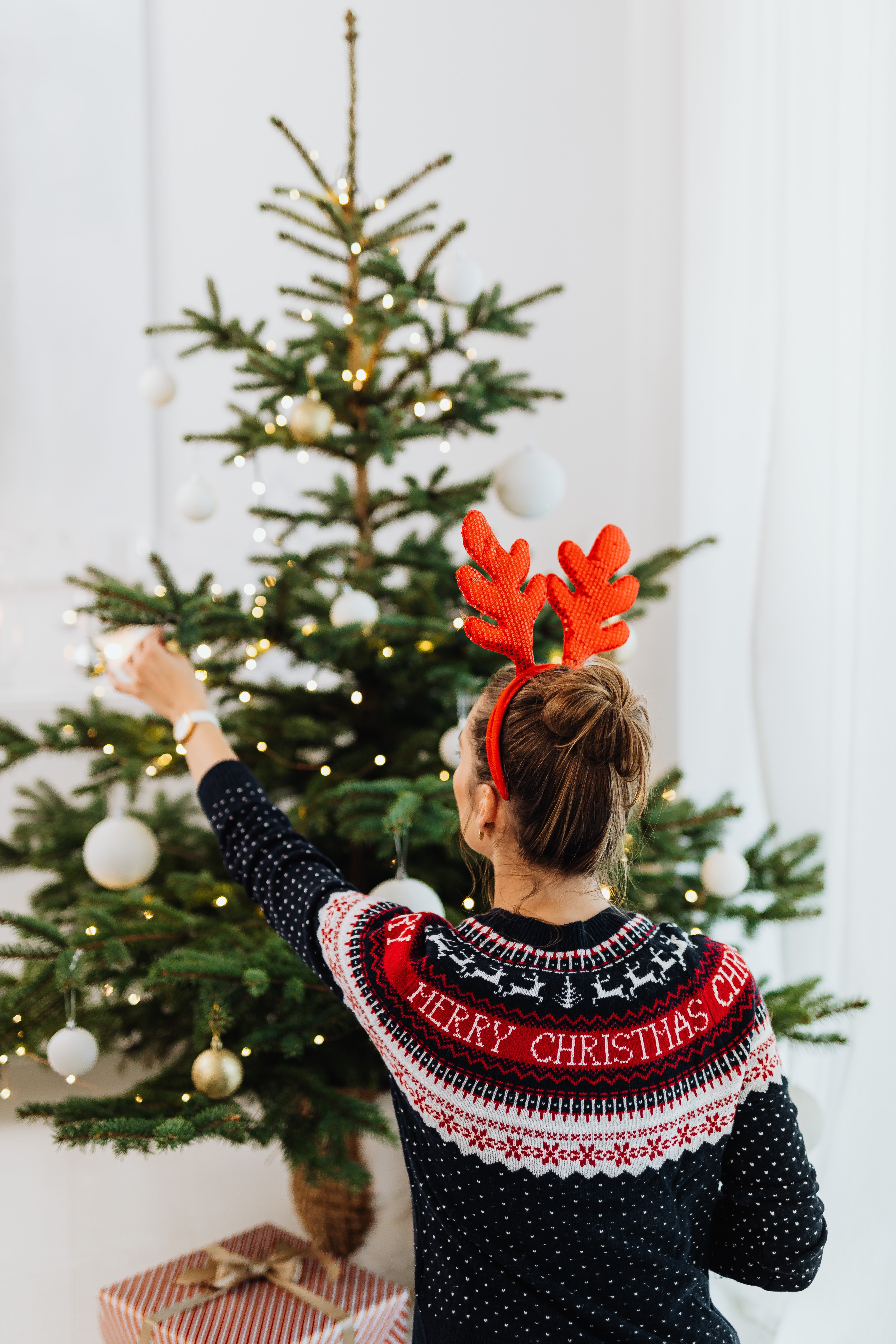 Una mujer decora un árbol de navidad. | Foto: Pexels