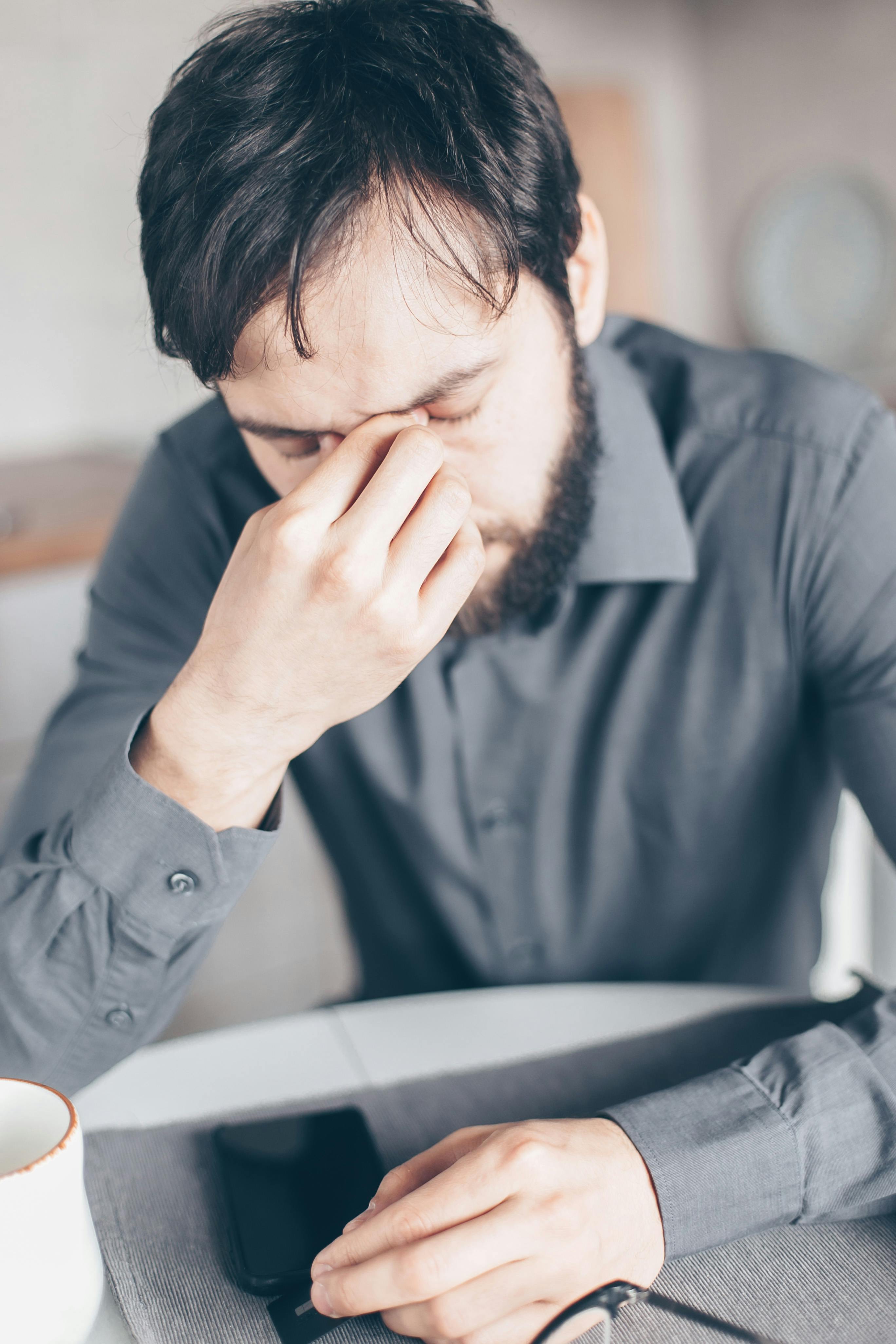 A stressed man sitting with his phone | Source: Pexels