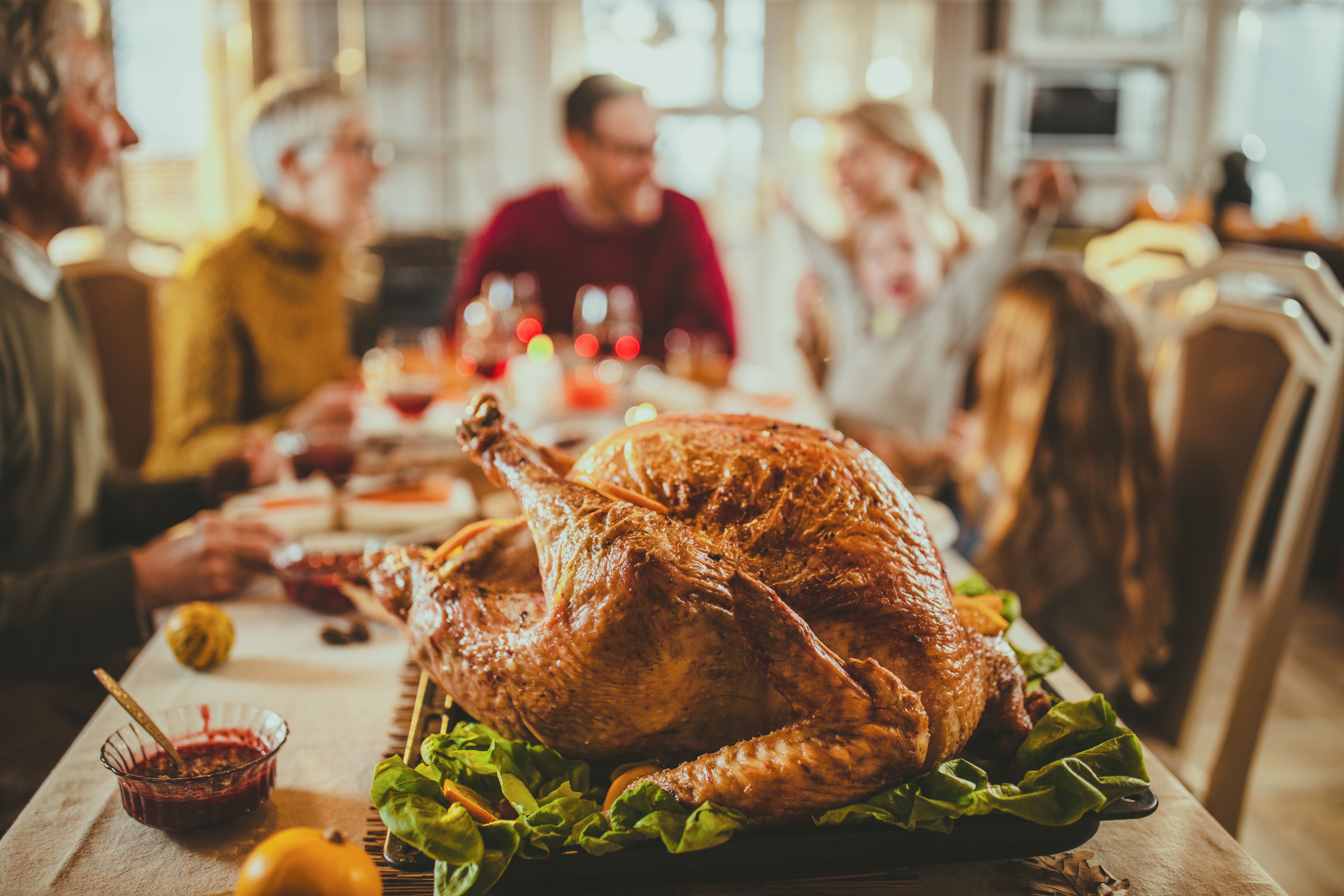 Turkey on the dinner table with a family behind. | Source: Getty Images