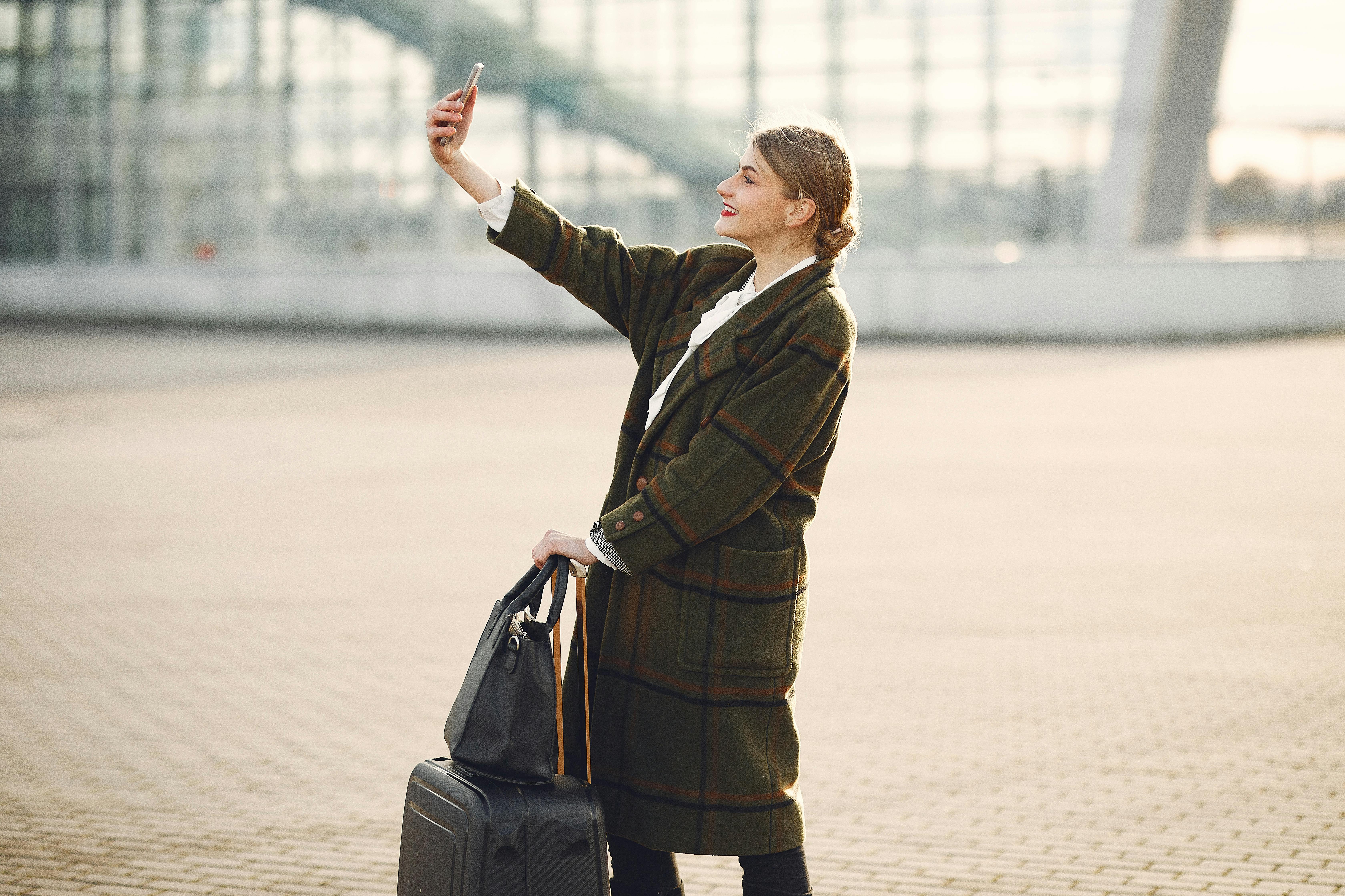 A woman peering at her phone at an airport | Source: Pexels