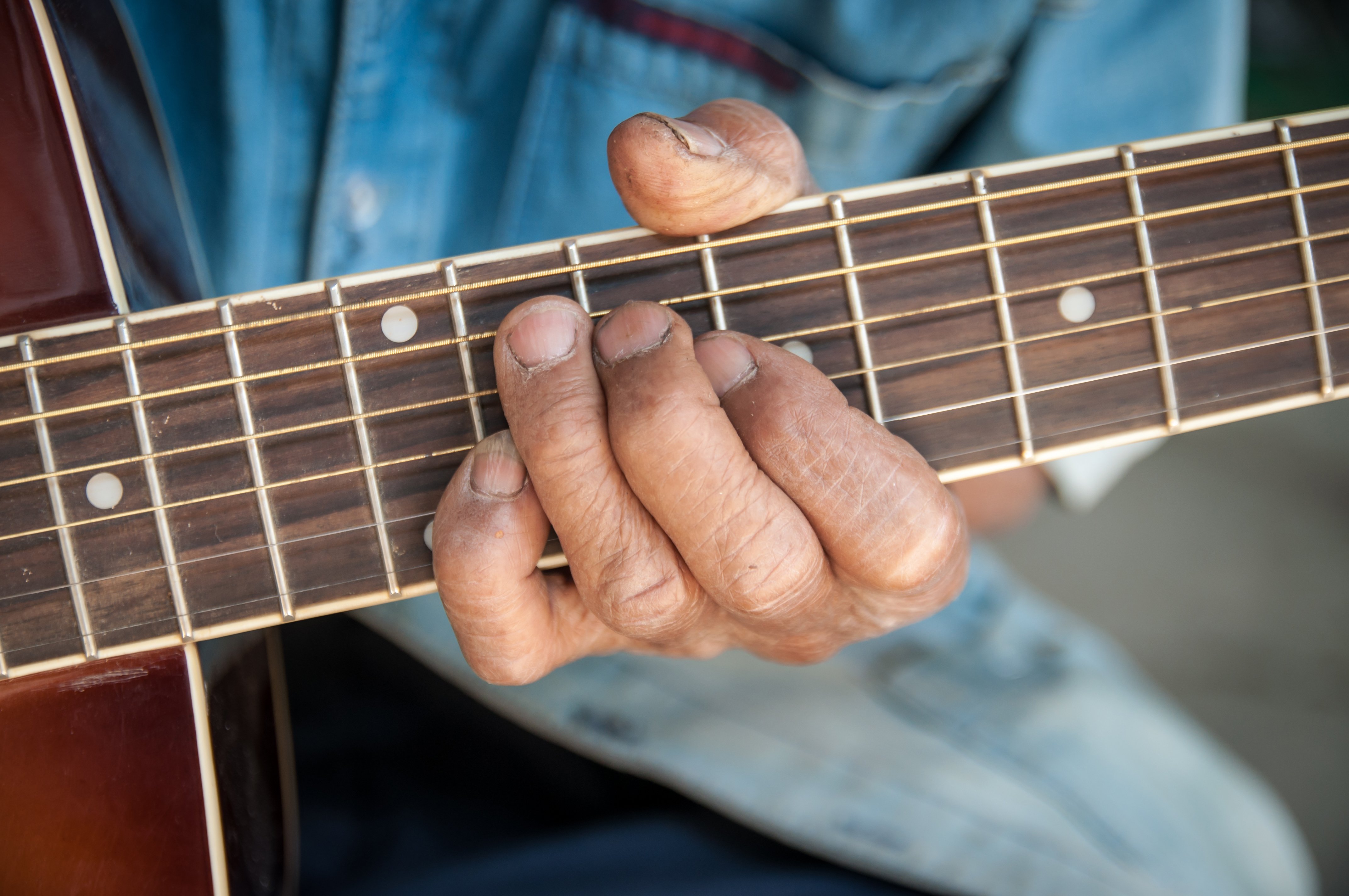 Manos de hombre mayor tocando una guitarra.| Foto: Shutterstock