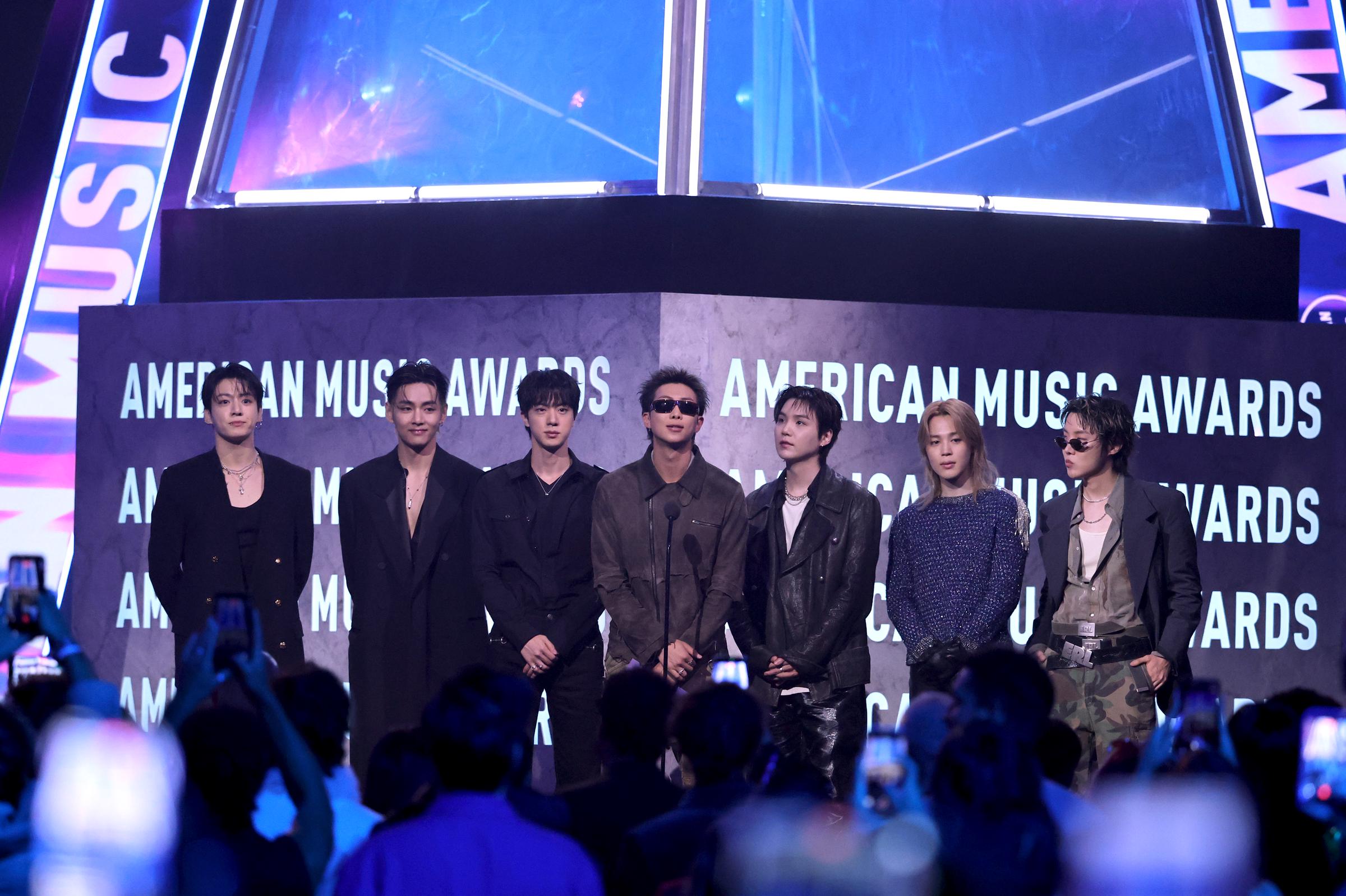 Jungkook, V, Jin, RM, Suga, Jimin and J-Hope of BTS delivered sleek modern menswear in a mix of tailored black layers, leather jackets, shimmering knits, and oversized silhouettes while addressing the crowd onstage.