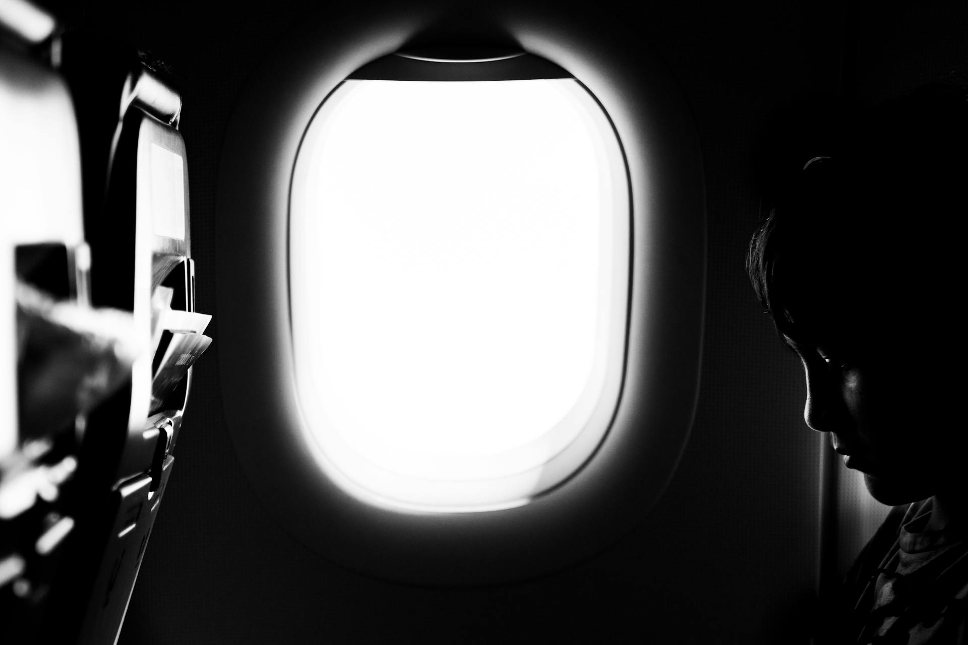 A grayscale photo of a boy sitting by the window in an airplane | Source: Pexels