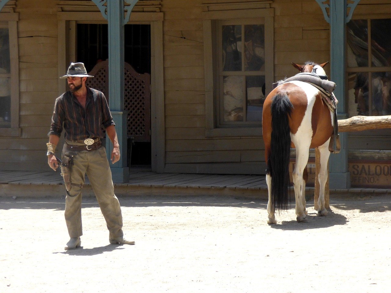 A cowboy looking confused as he looks around with a horse close by | Photo: Pixabay