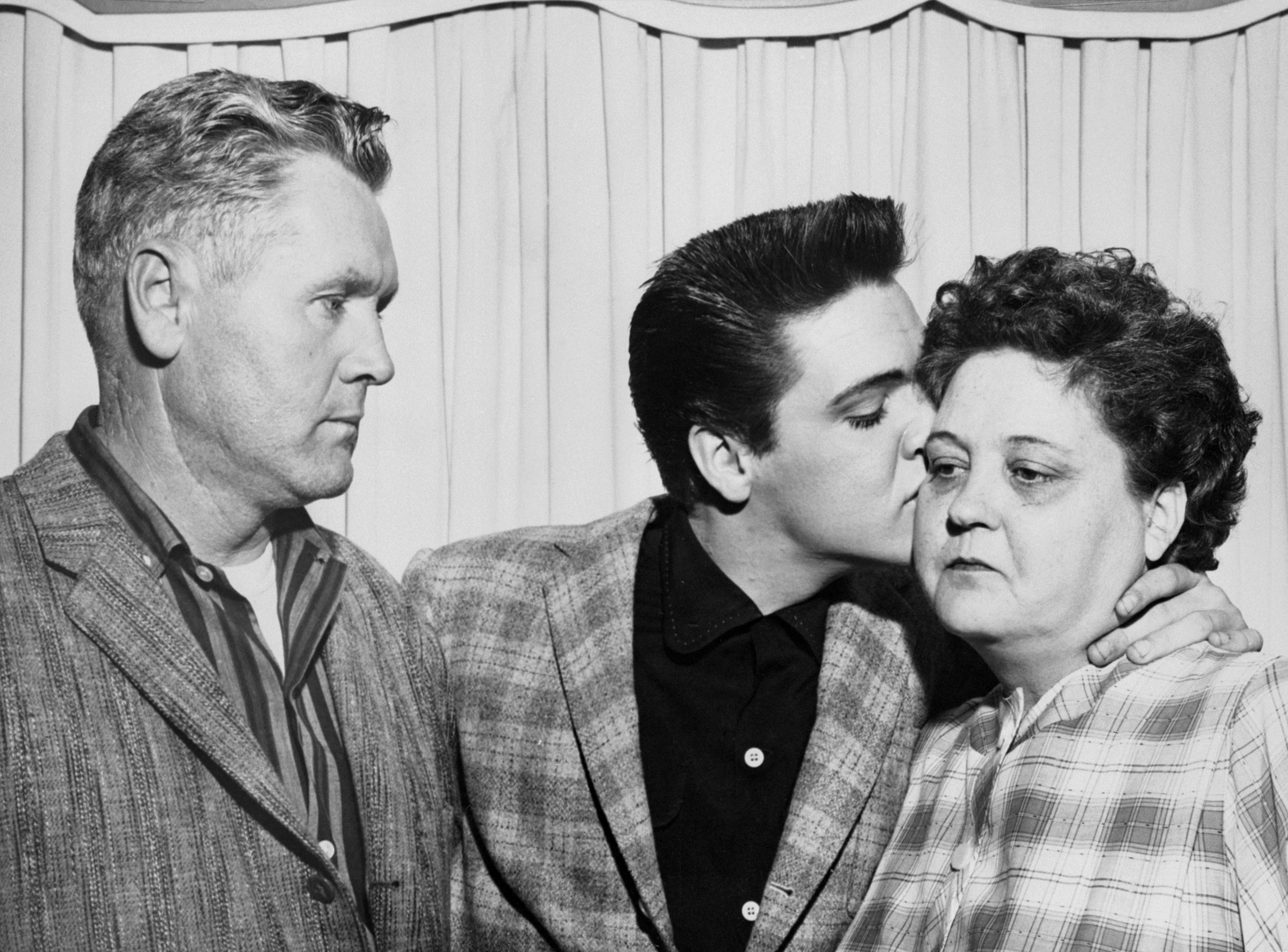 Elvis Presley besa a su madre, Gladys Love, en la víspera de su incorporación al ejército al lado de su padre, Vernon Presley, en 1958 | Foto: Getty Images