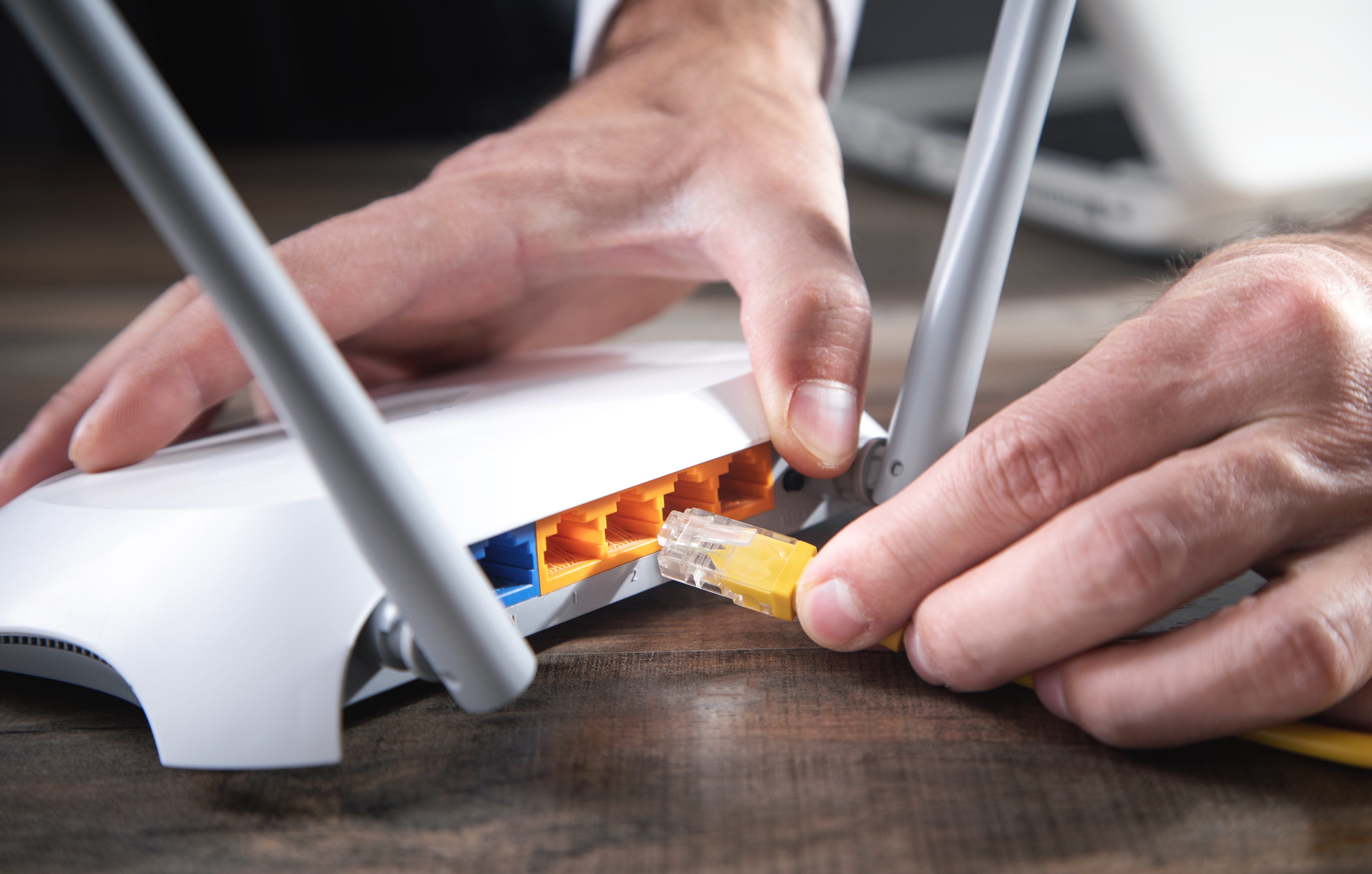 A man plugging a cable into an internet router | Source: Shutterstock