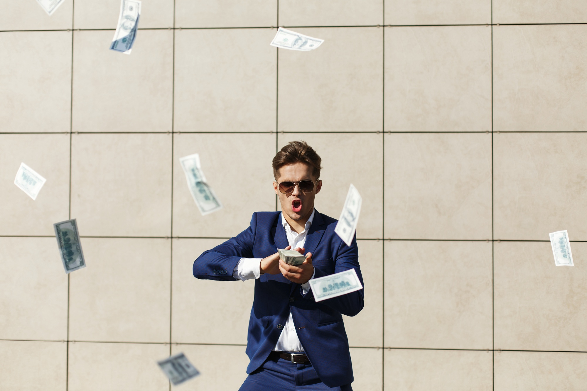 A man wearing sunglasses and a suit while throwing money around in the street | Source: Freepik