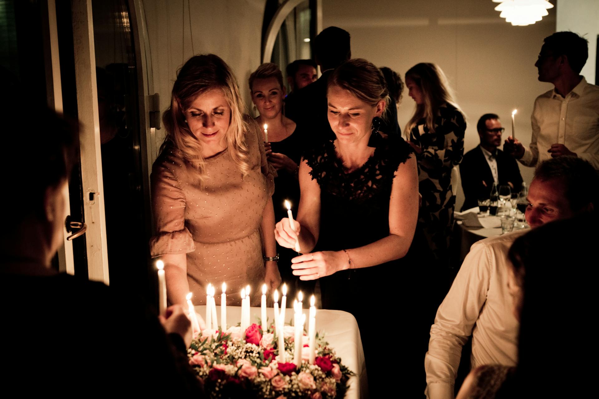 Two women holding candles at a birthday party | Source: Pexels