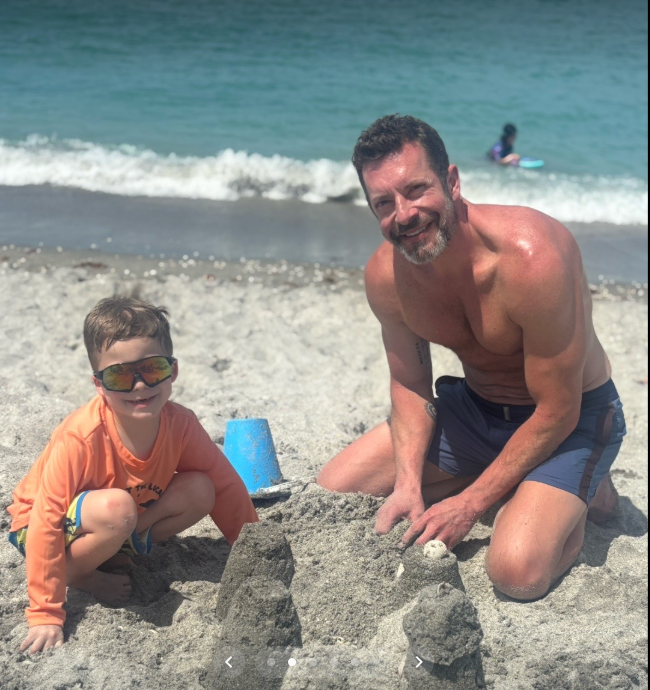 Kristopher Karolkiewicz kneels beside one of the couple's young sons as they build sandcastles together on a beach during the family's spring break vacation. | Source: TikTok/mandykarolk