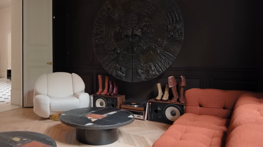 A styled corner of the library features a large circular bronze relief sculpture, vintage audio equipment, and a collection of iconic leather boots belonging to James Brown. | Source: YouTube/@Archdigest