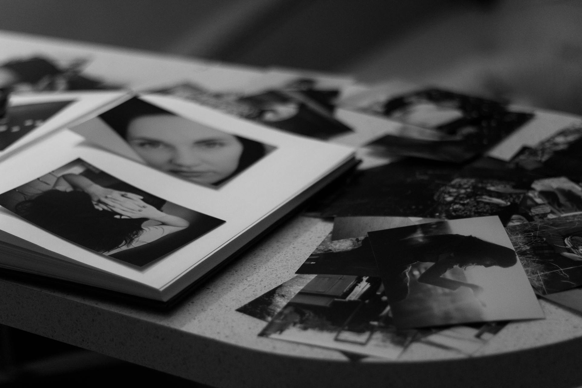 Close-up of a photo album and grayscale photographs on a table | Source: Pexels