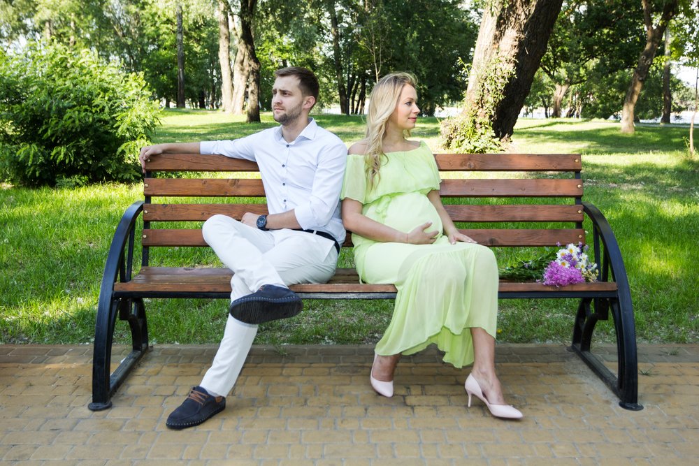 A pregnant wife and husband on a bench in the park, having a quarrel. | Photo: Shutterstock.