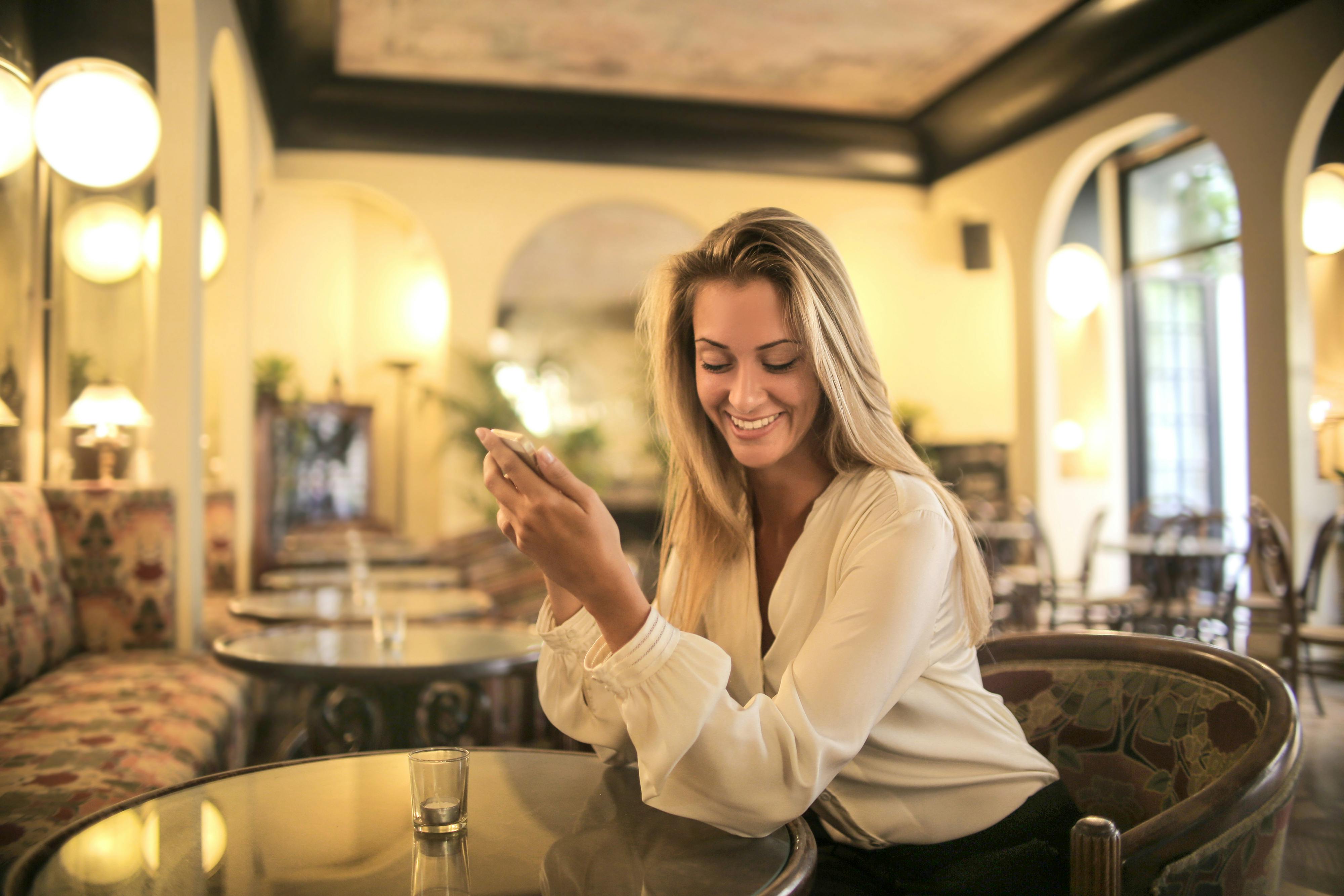 A woman texting while at a restaurant | Source: Pexels