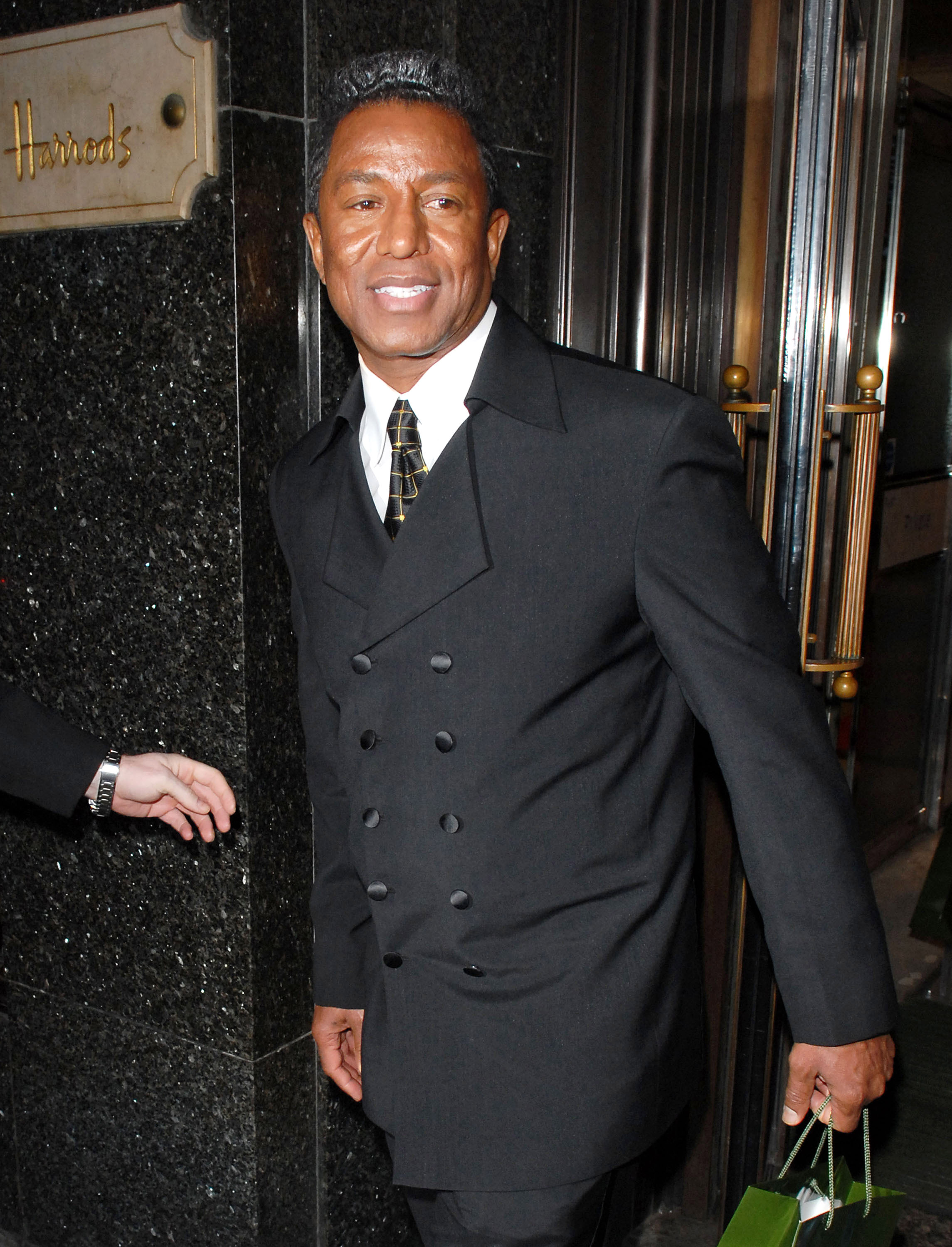 ermaine Jackson steps out of Harrods in a sharp double-breasted suit, pairing classic tailoring with a modern edge. Holding a shopping bag and glancing to the side, he exudes understated luxury and effortless sophistication.