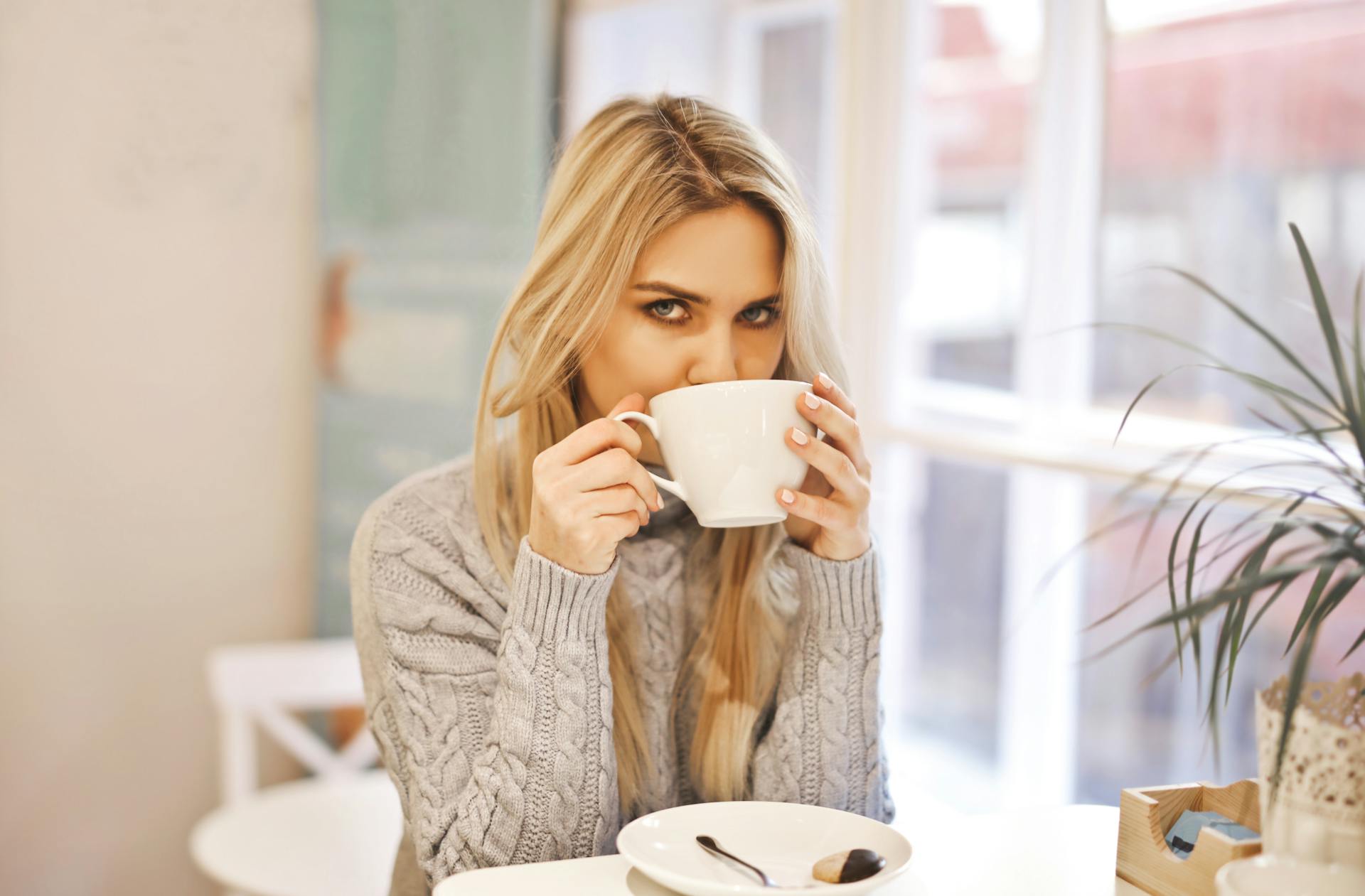 A woman looking at someone while holding a white ceramic mug | Source: Pexels