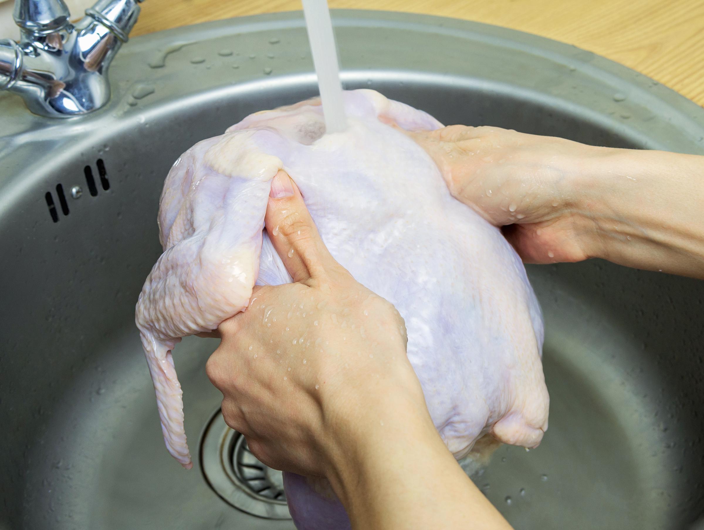A woman washing her raw chicken in the kitchen sink | Source: Getty Images