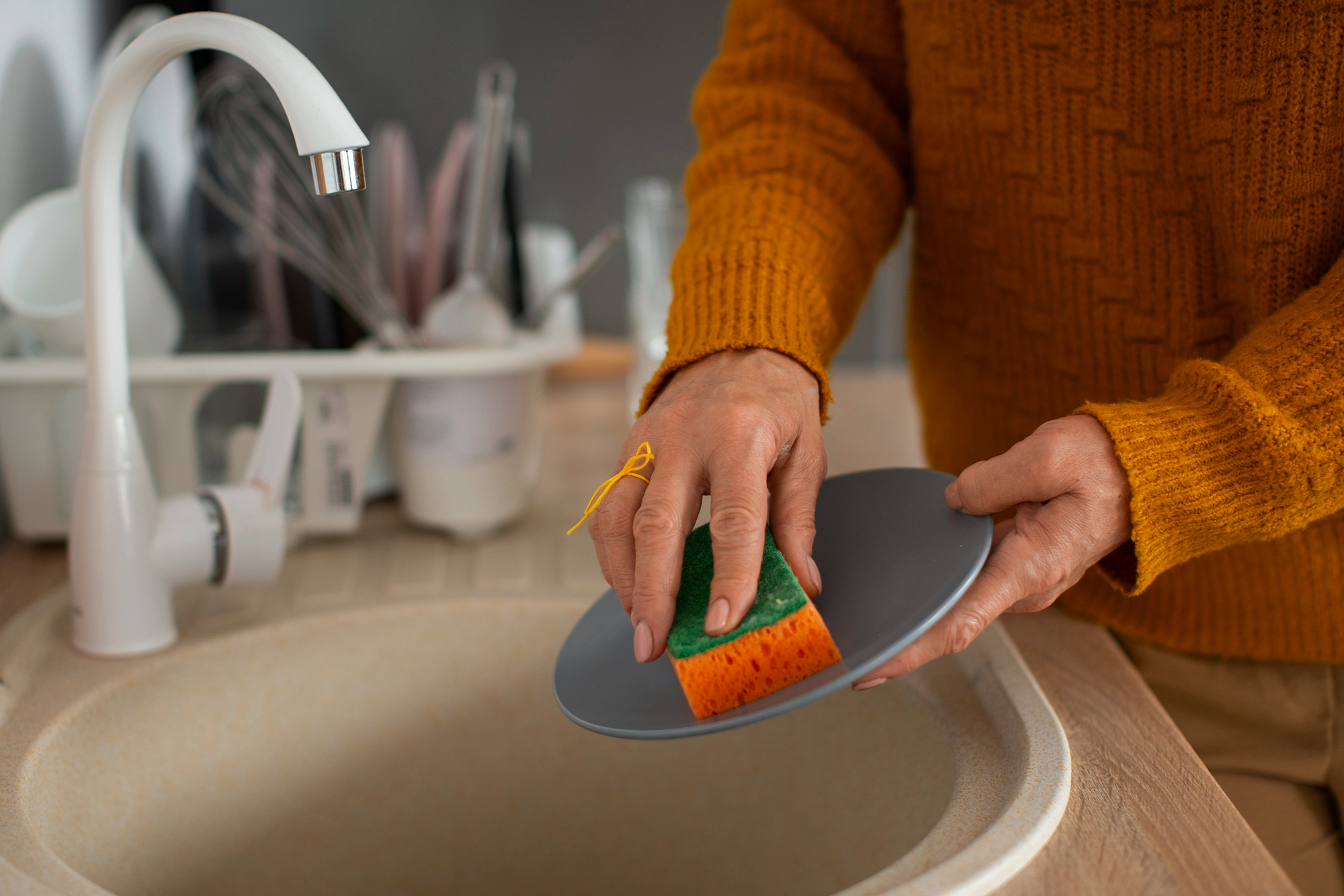 A woman cleaning a plate with a sponge | Source: Freepik