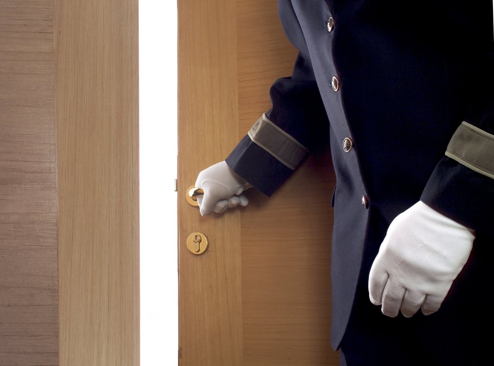 Hoteldiener öffnet die Zimmertür für einen Gast. | Quelle: Shutterstock