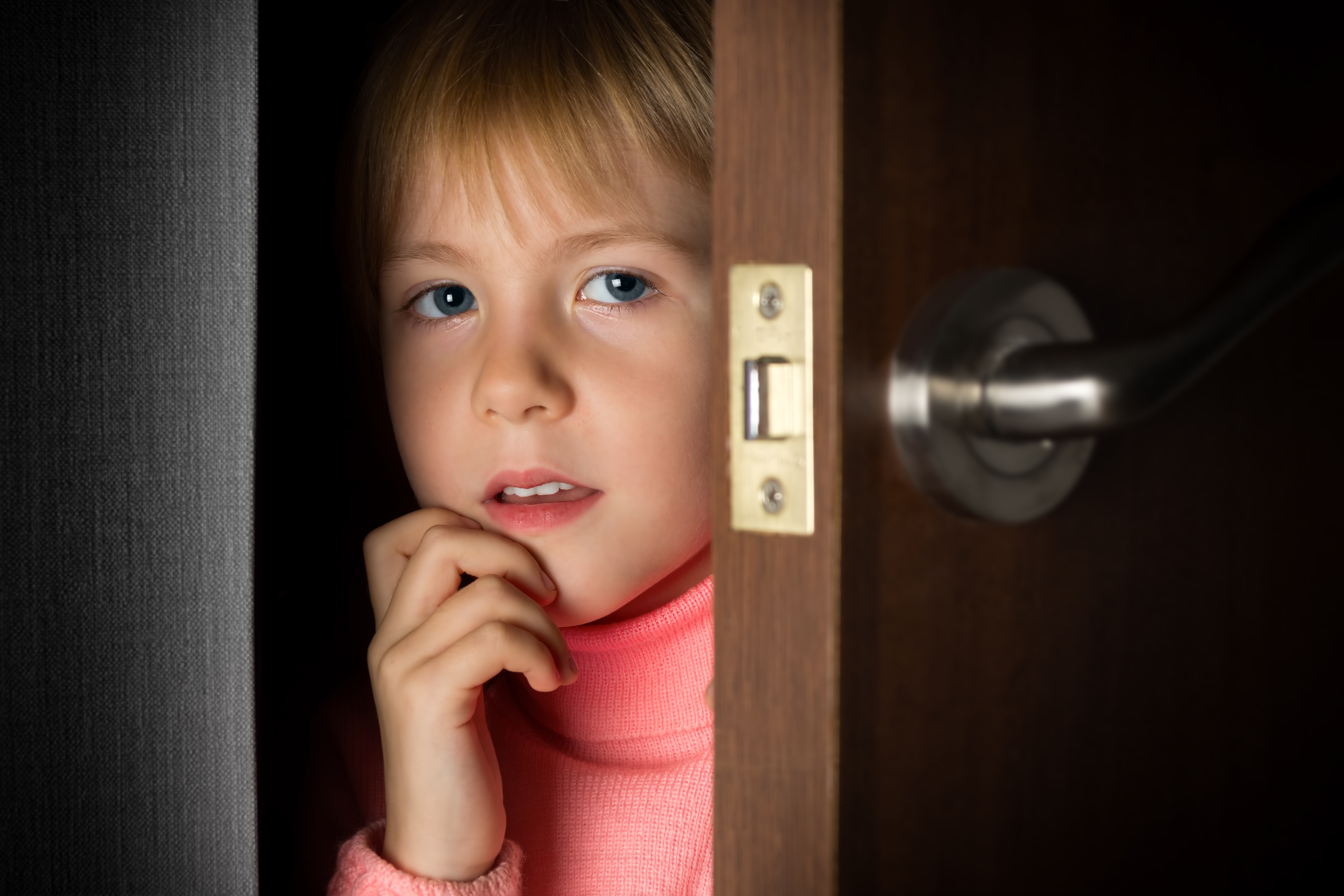 A little girl peeking through a door | Source: Shutterstock
