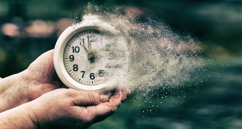 Manos sosteniendo un reloj que se disuelve en pequeñas partículas. | Foto: Shutterstock Manos sosteniendo un reloj que se disuelve en pequeñas partículas. | Foto: Shutterstock