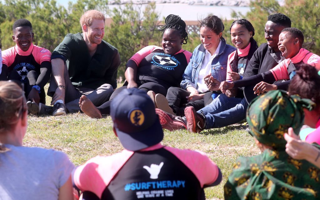 Prince Harry and Meghan join surf mentors and participate in a group activity as they visit Waves for Change, an NGO, at Monwabisi Beach. | Source: Getty Images