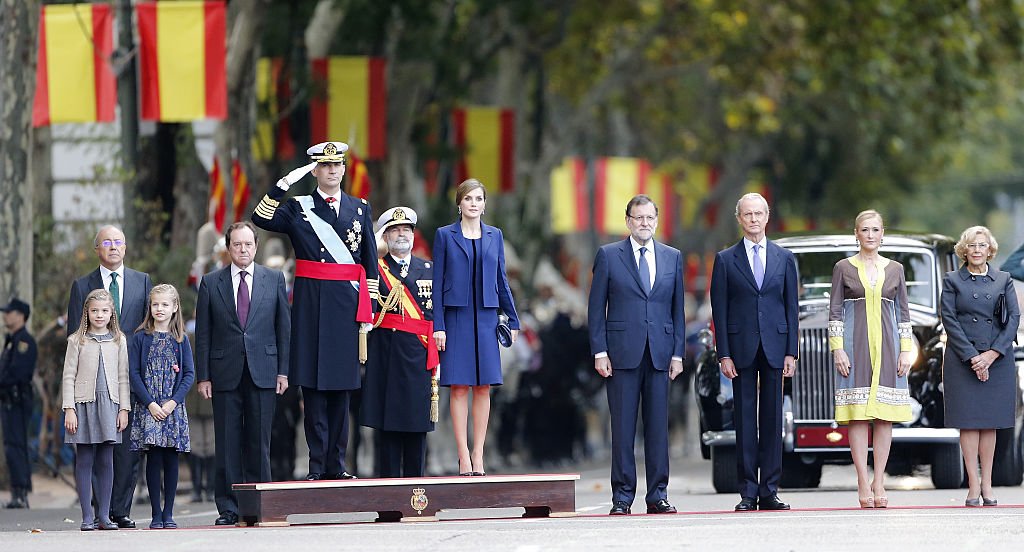 Sofía de España con la Princesa Leonor, el Rey Felipe VI, la Reina Letizia de España, el Primer Ministro Mariano Rajoy, el Ministro Pedro Morenes, la Presidenta de la Comunidad de Madrid Cristina Cifuentes y la Alcaldesa de Madrid Manuela Carmena en el Desfile Militar del Día Nacional de 2015. | Foto: Getty Images