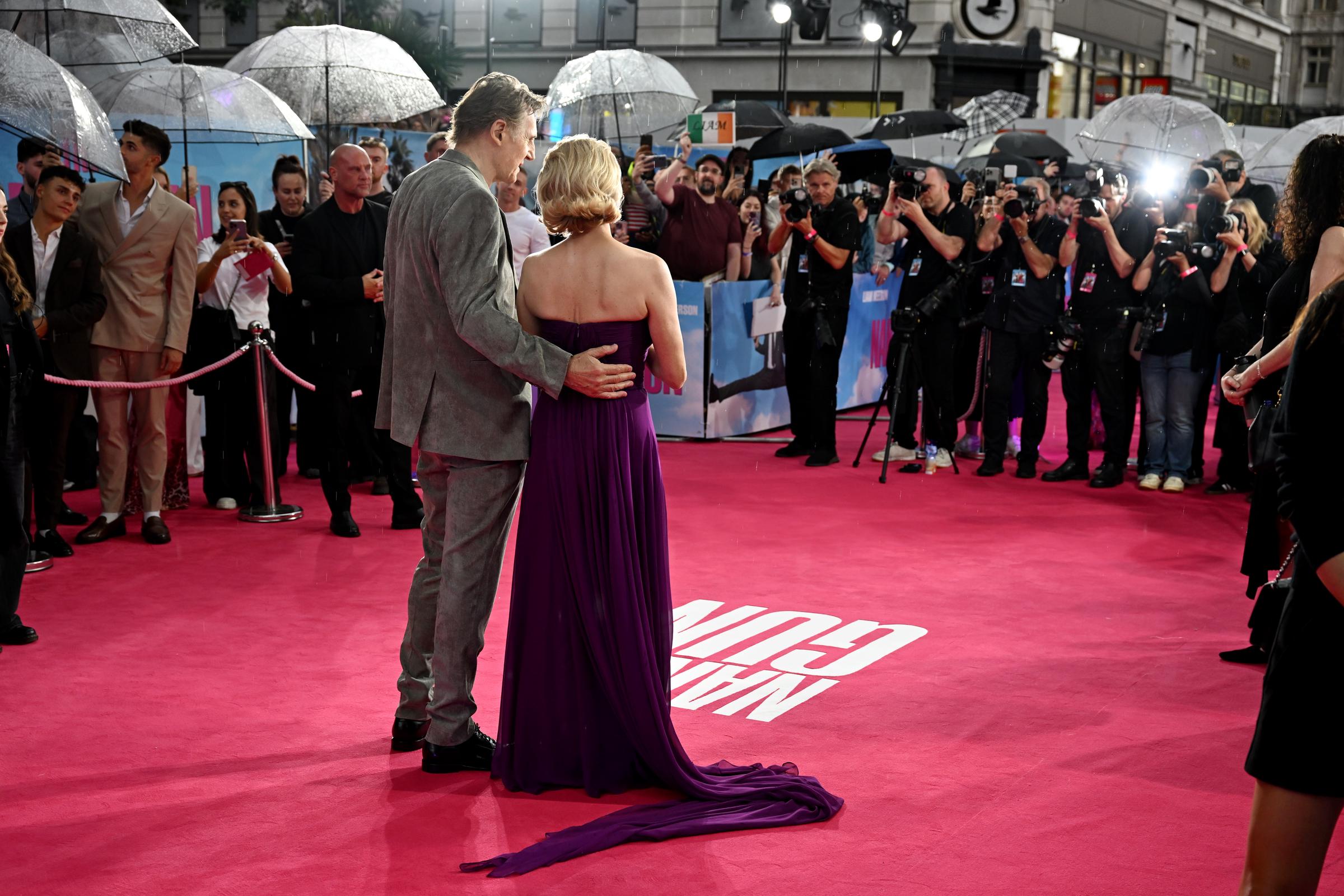 Liam Neeson holds Pamela Anderson's waist as the pair take photos at the UK premiere for "The Naked Gun" at Cineworld Leicester Square, in London, England on July 22, 2025 | Source: Getty Images