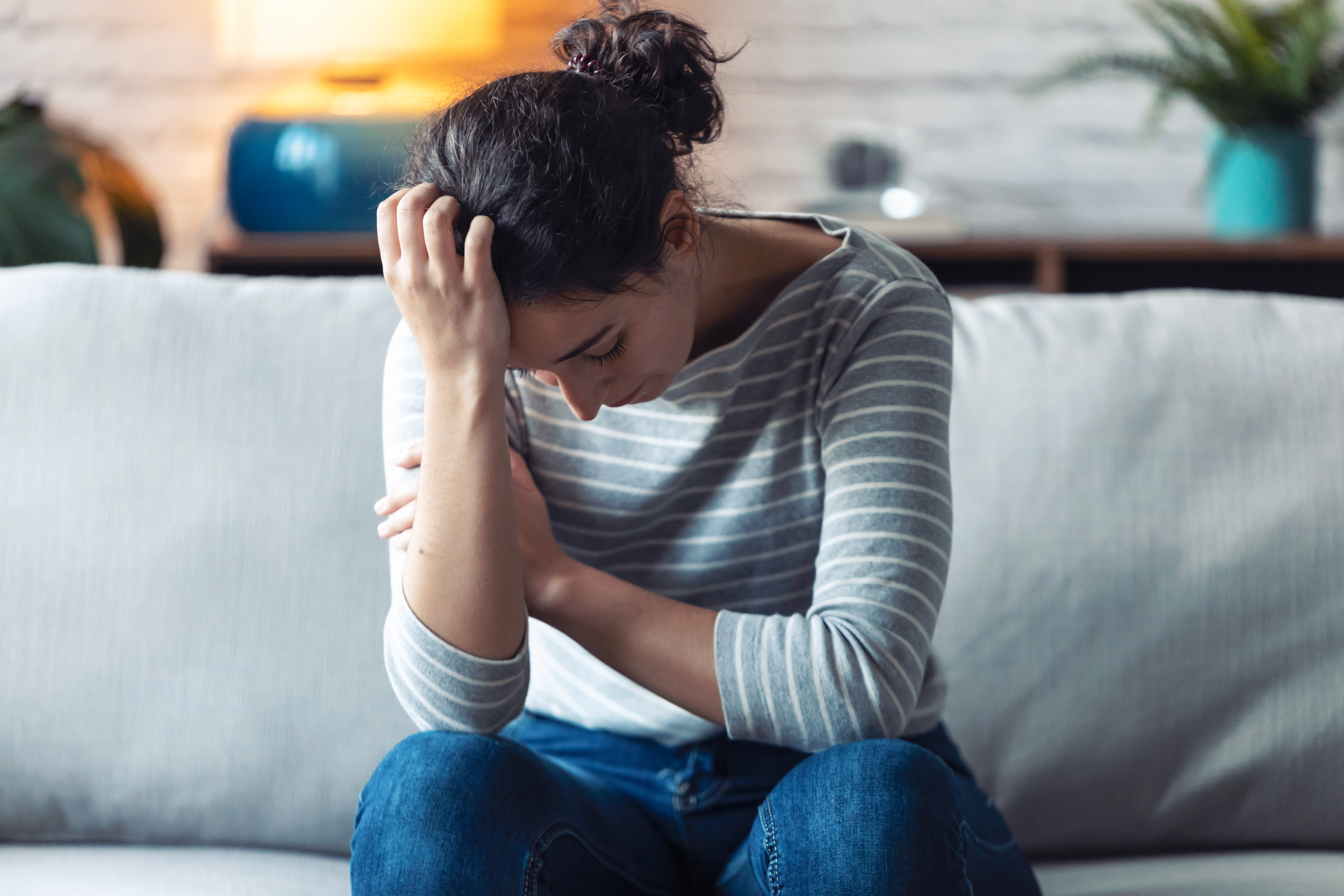 A woman sitting on the couch looking sad | Source: Shutterstock