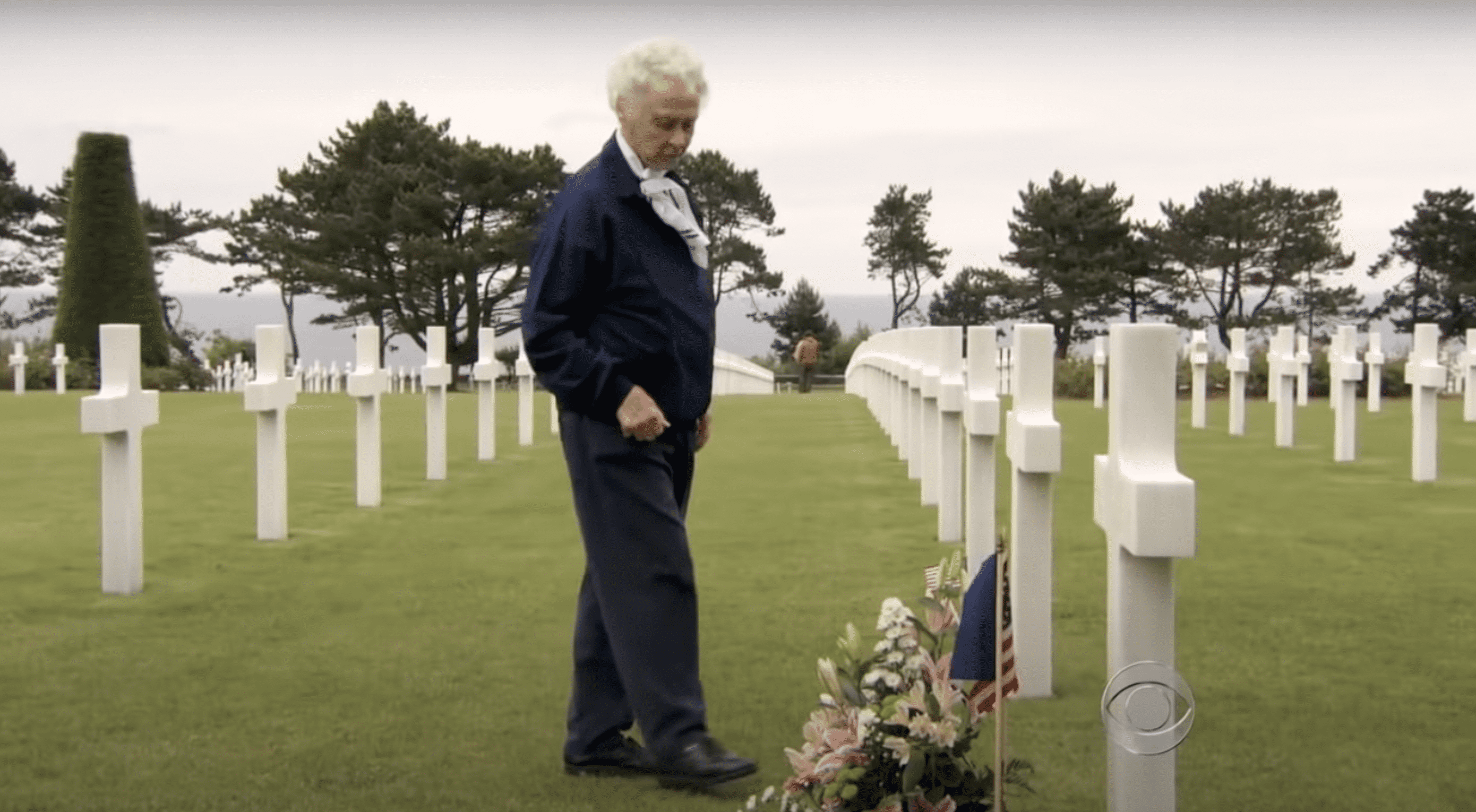Peggy Harris steht neben dem mit Blumen geschmückten Grab ihres verstorbenen Mannes Billie Harris. | Quelle: YouTube.com/CBS News