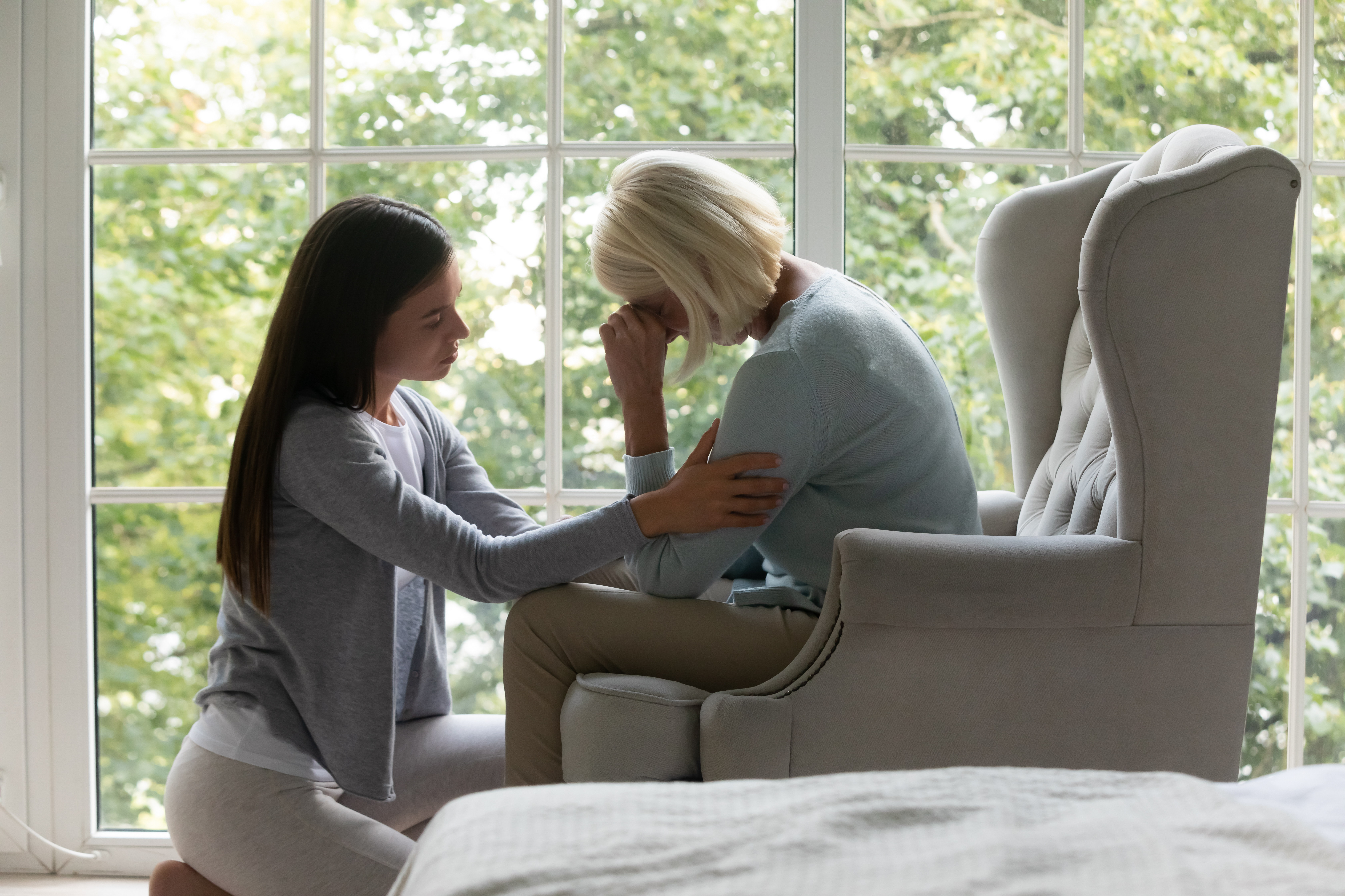 A young woman comforting her depressed senior mom | Source: Shutterstock