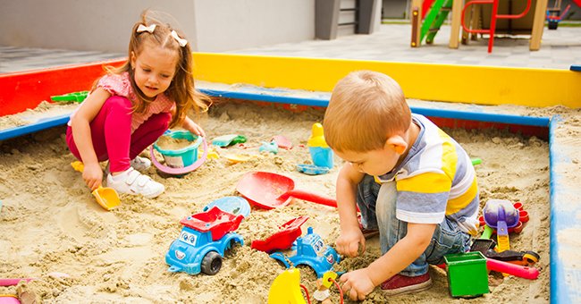 Two young children playing in a sandbox. | Photo: Shutterstock