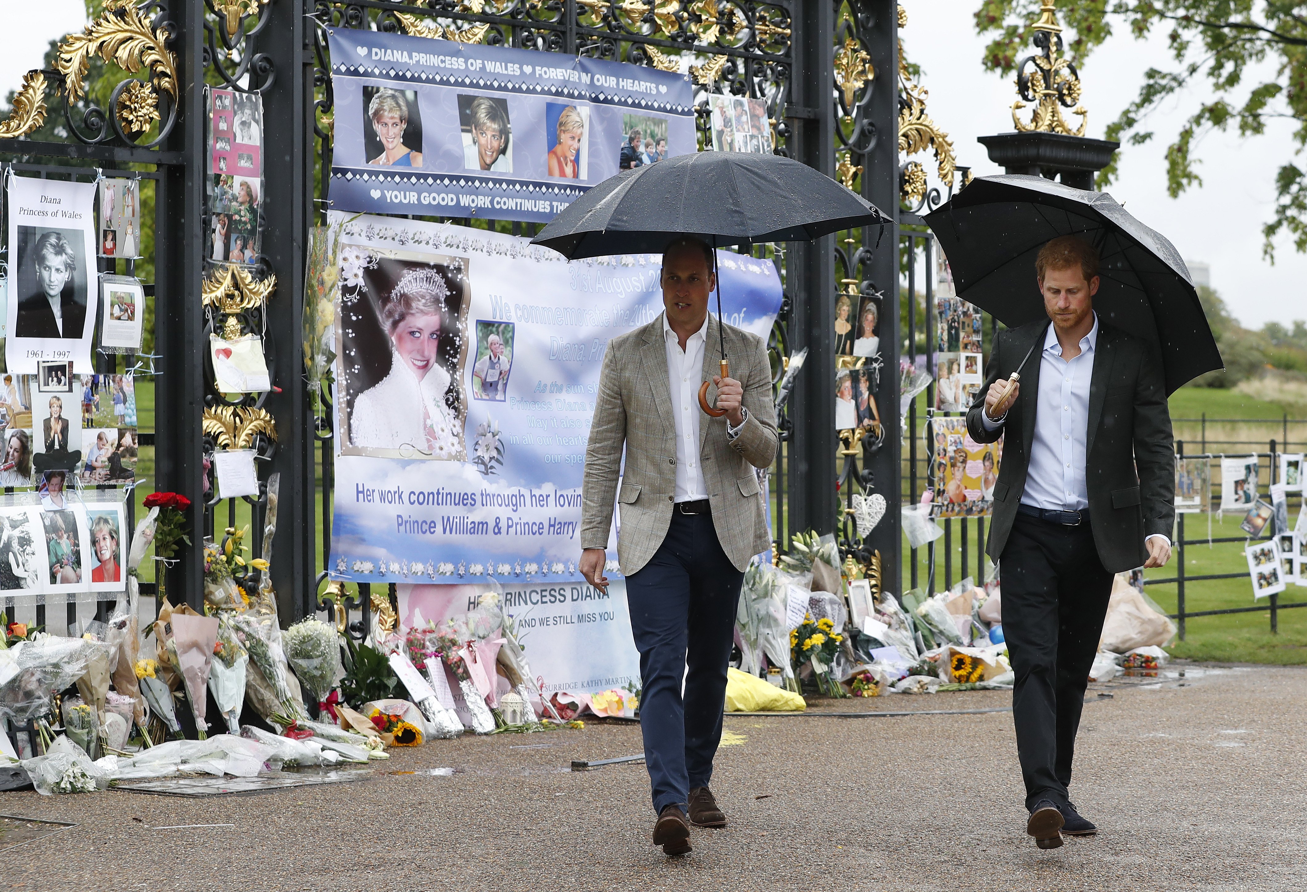 Prince William and Prince Harry walk away after placing flowers amongst the floral and pictorial tributes to their late mother, Princess Diana. | Source: Getty Images