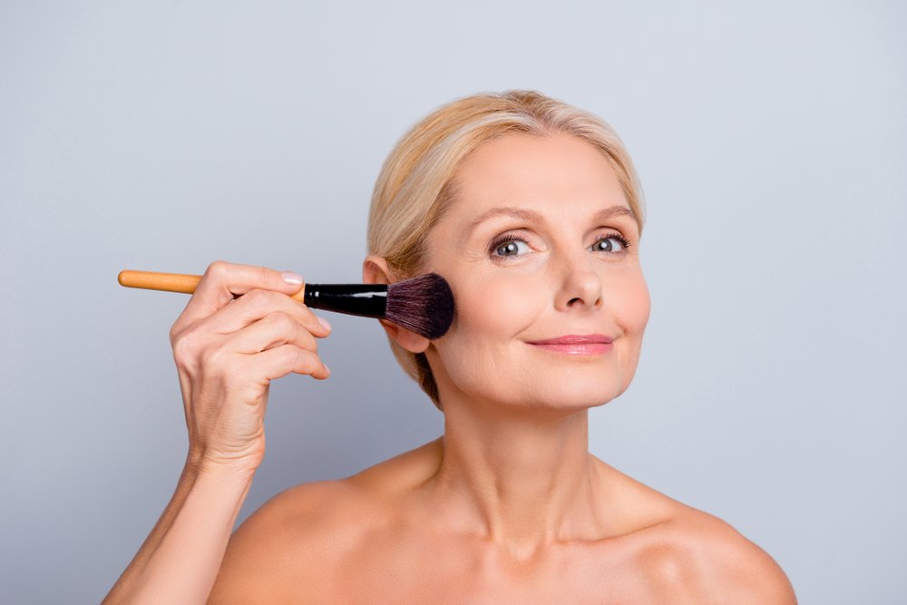 Retrato de mujer con piel perfecta aplicando maquillaje con una brocha. | Foto: Shutterstock