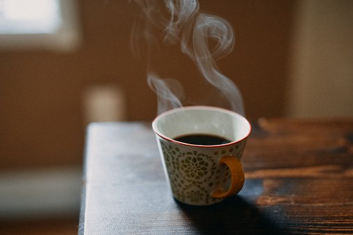 Tasse à café avec vapeur chaude sur une table en bois. | Photo : Getty Images