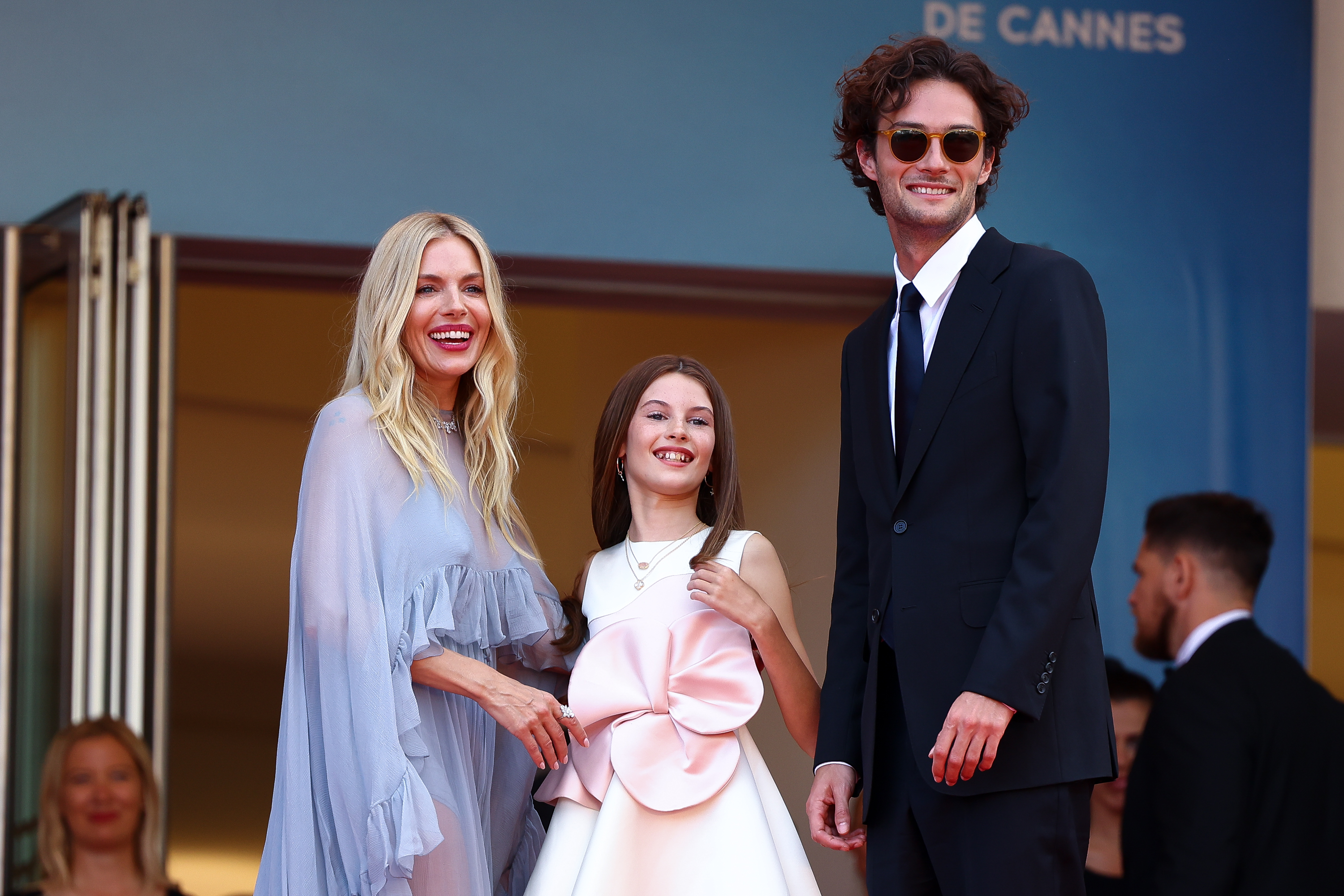 (L-R) Sienna Miller, Marlowe Sturridge, and Oli Green attend the "Horizon: An American Saga" Red Carpet at the 77th annual Cannes Film Festival at Palais des Festivals on 19 May 2024 in Cannes, France. | Source: Getty Images