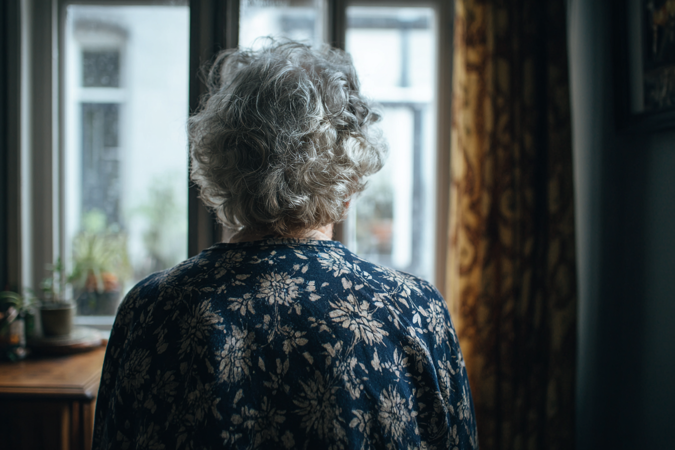 An older woman standing near a window | Source: Midjourney