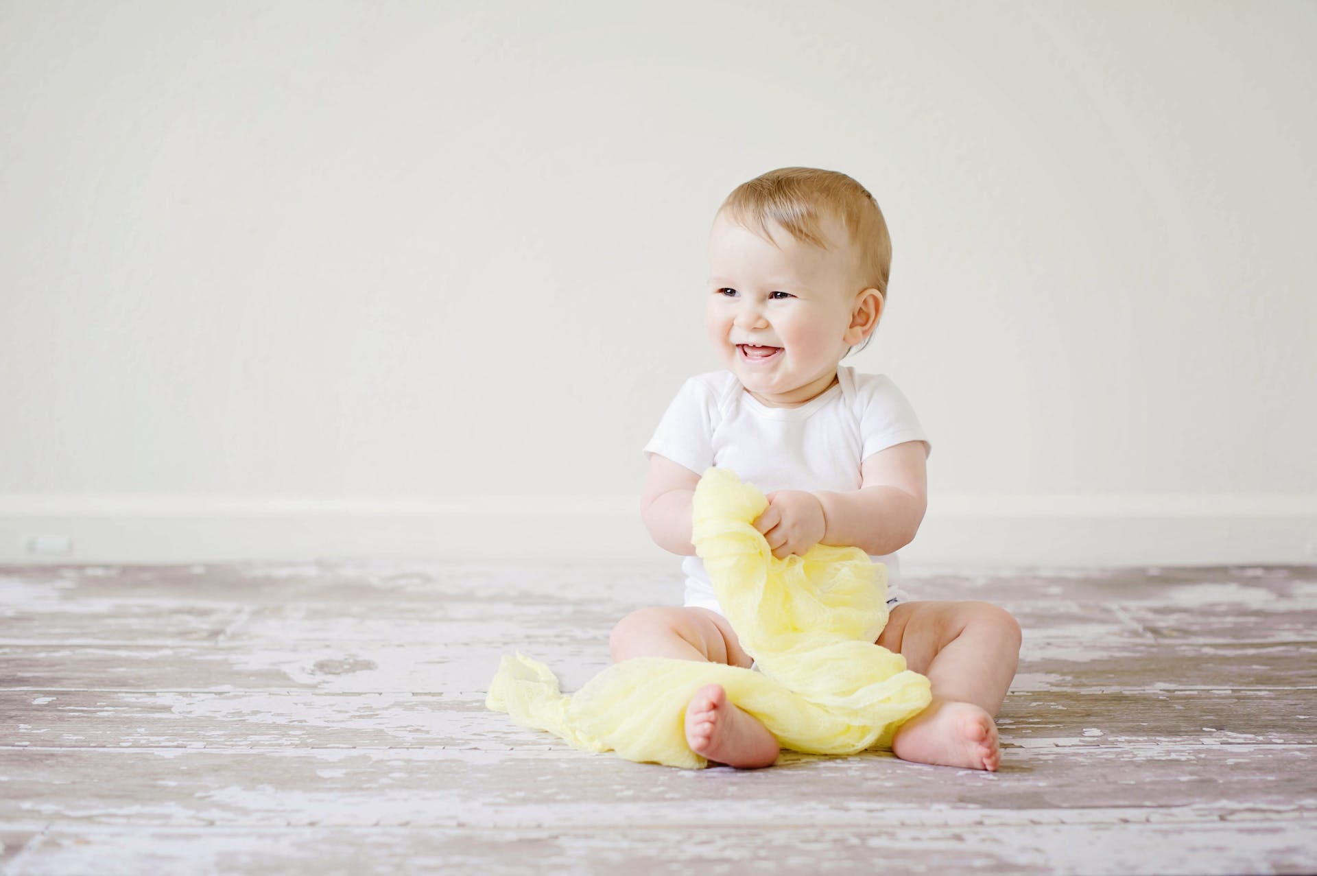A baby laughing while sitting on the floor | Source: Pexels