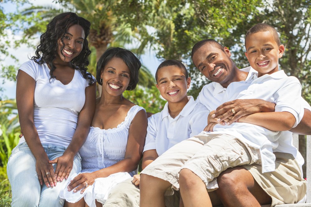 A family of two parents and three children sitting together outside. | Photo: Shutterstock