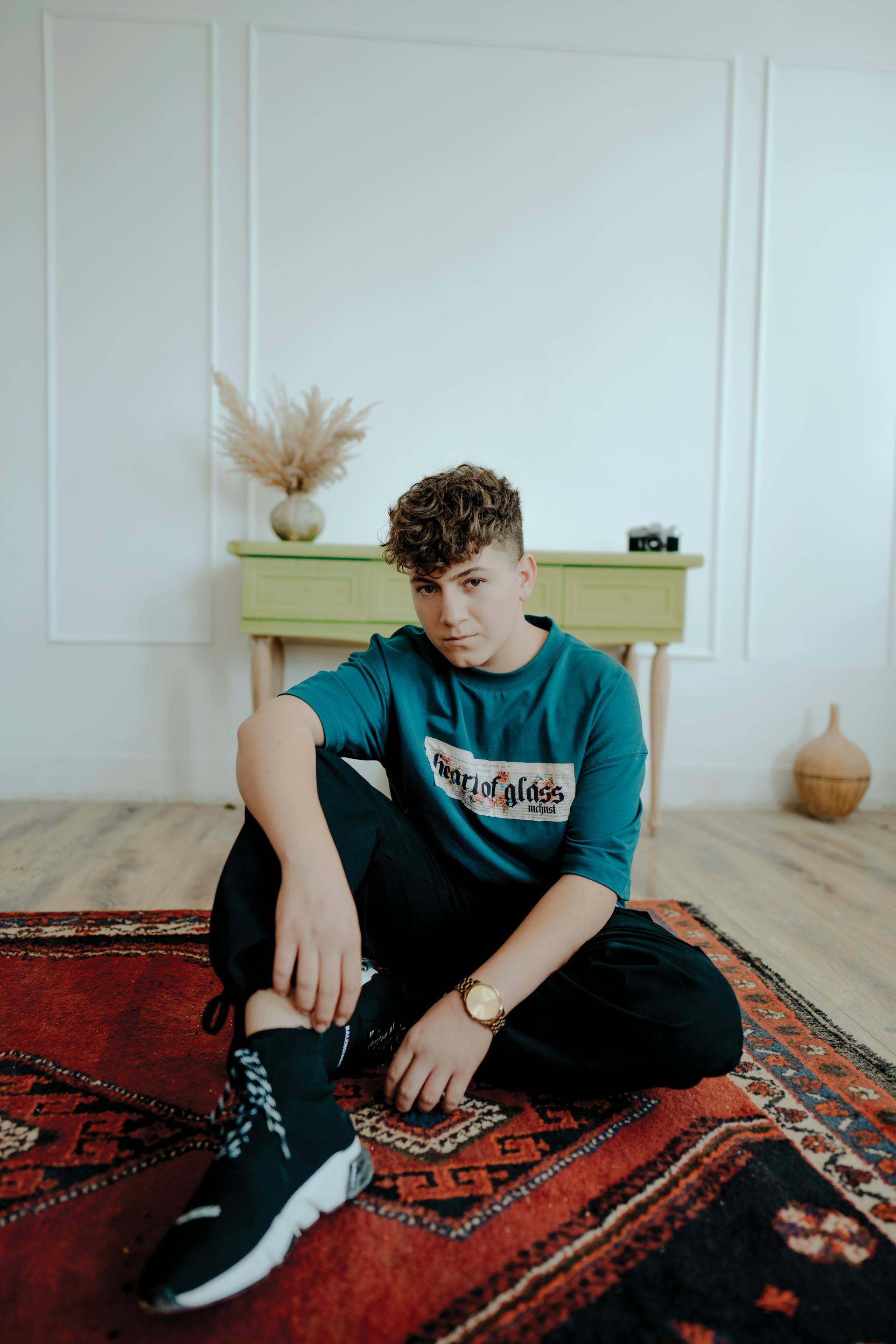 A teenage boy sitting on a carpet | Source: Pexels