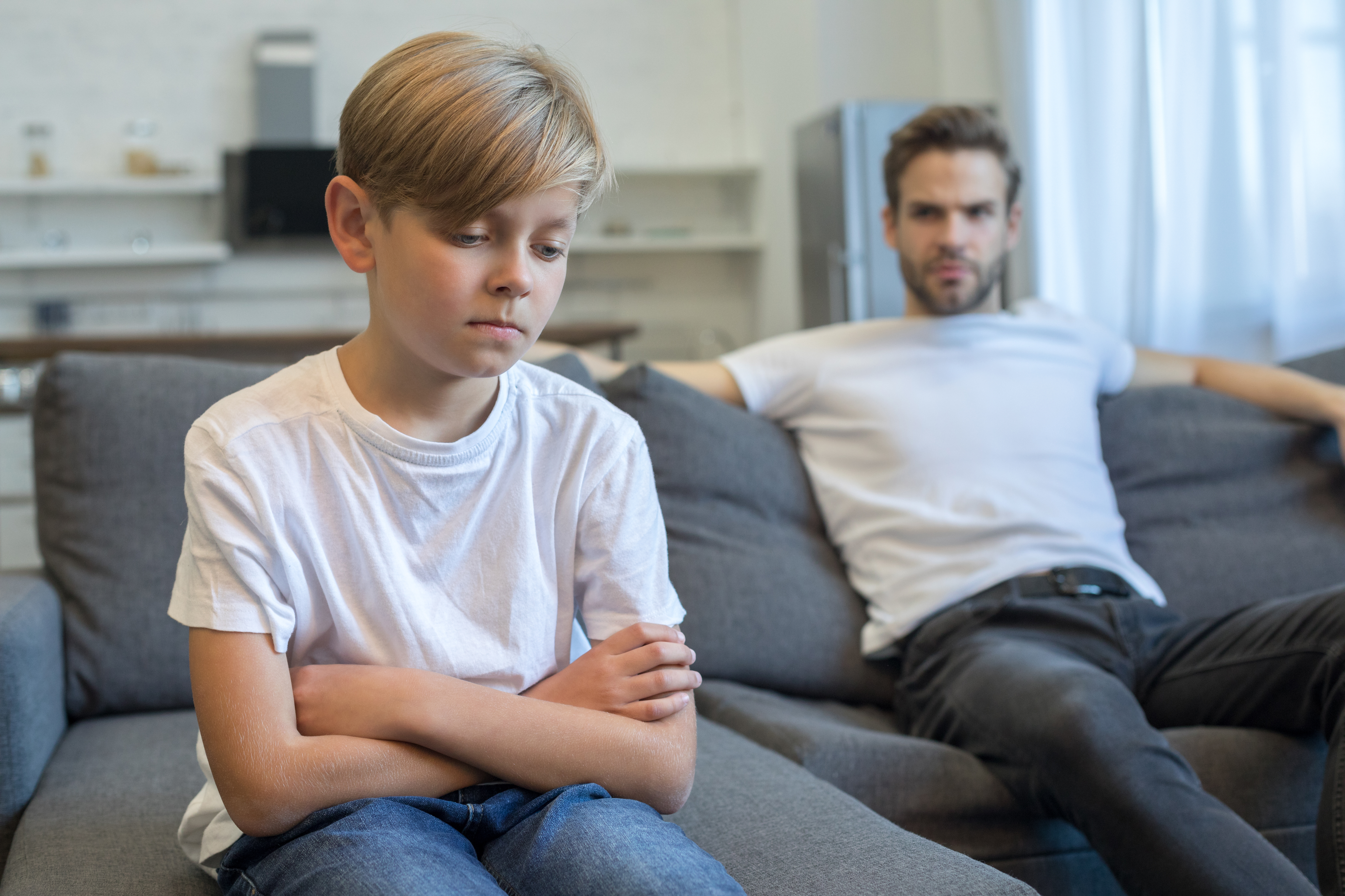 Enfant triste et ennuyé sur le canapé de la maison se sentant frustré | Source : Getty Images