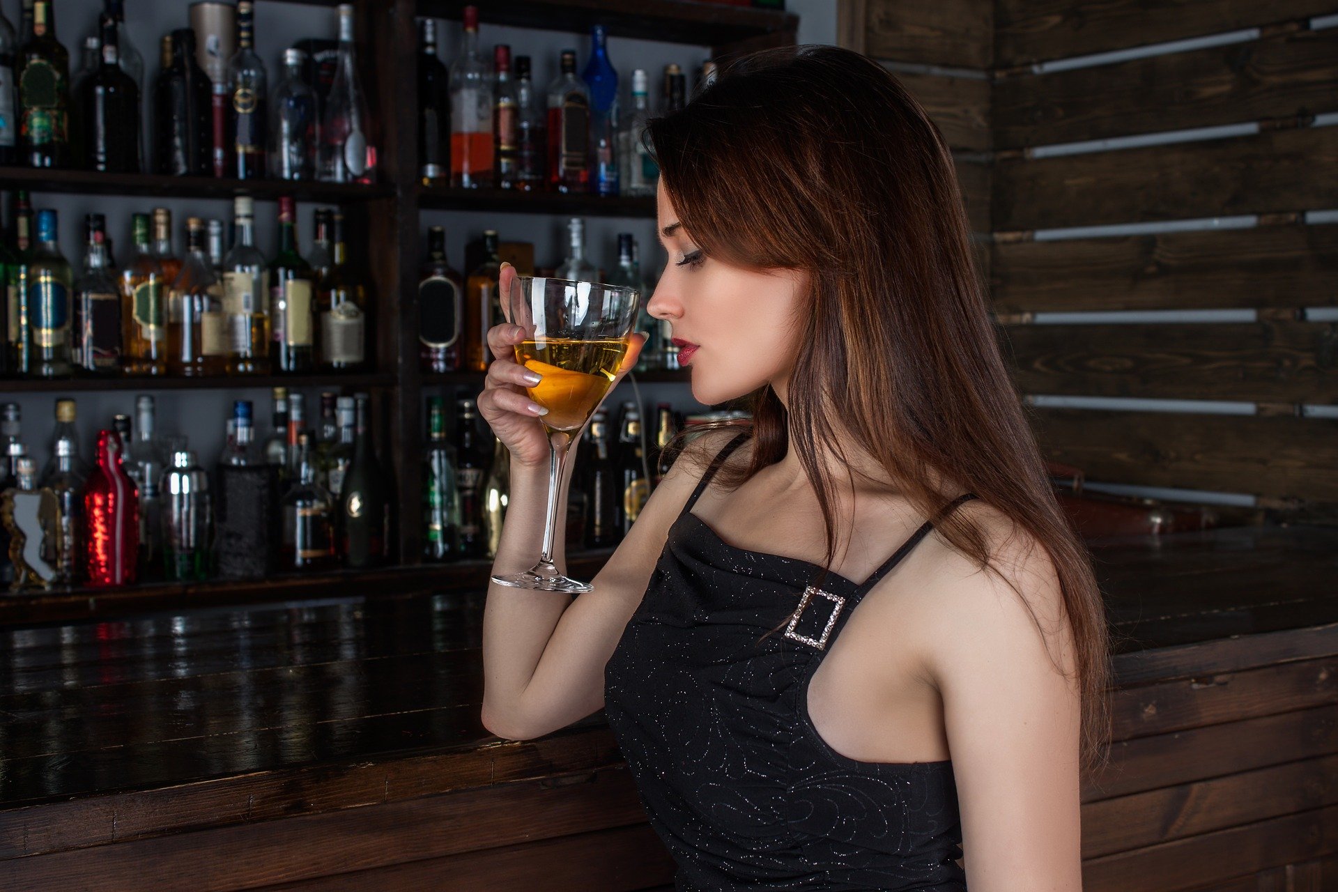 A beautiful young woman sitting alone at the bar drinking. | Photo: Pixabay.