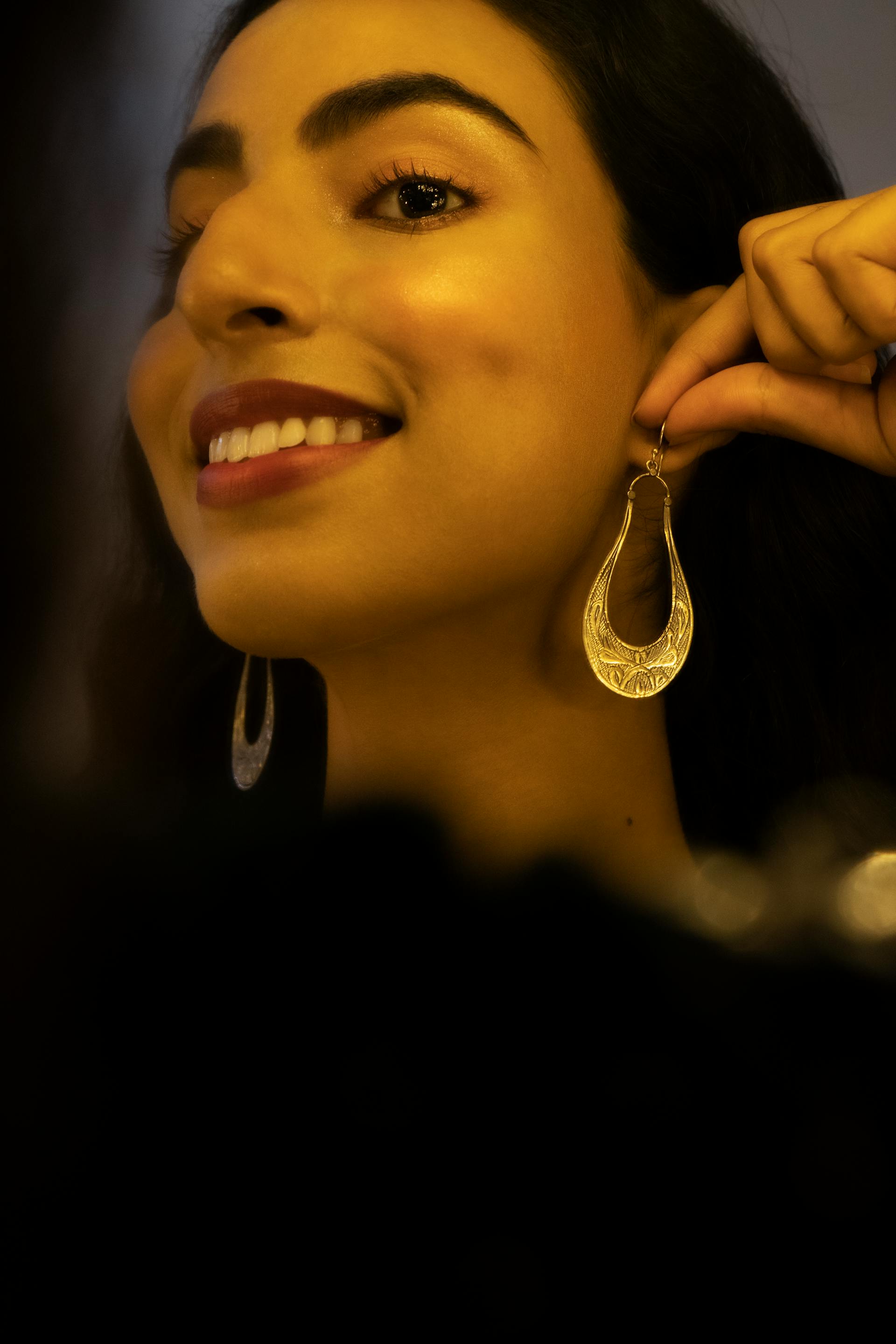 A woman putting on earrings | Source: Pexels