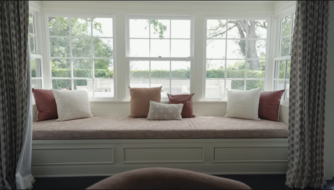 The perfect view! This sun-drenched window seat is piled high with earthy pillows, making it a favorite spot for the kids to chill. | Source: YouTube/@Archdigest