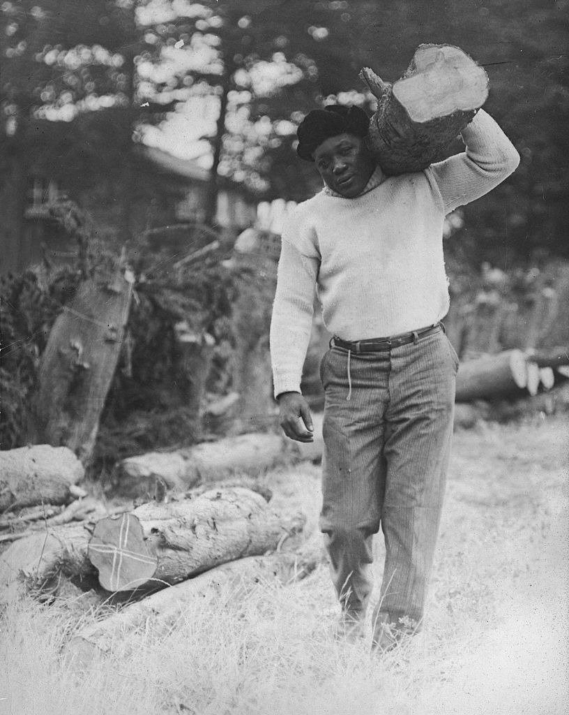 American boxer Jack Johnson hauls wood on his shoulder, early 1920s. | Photo: Getty Images