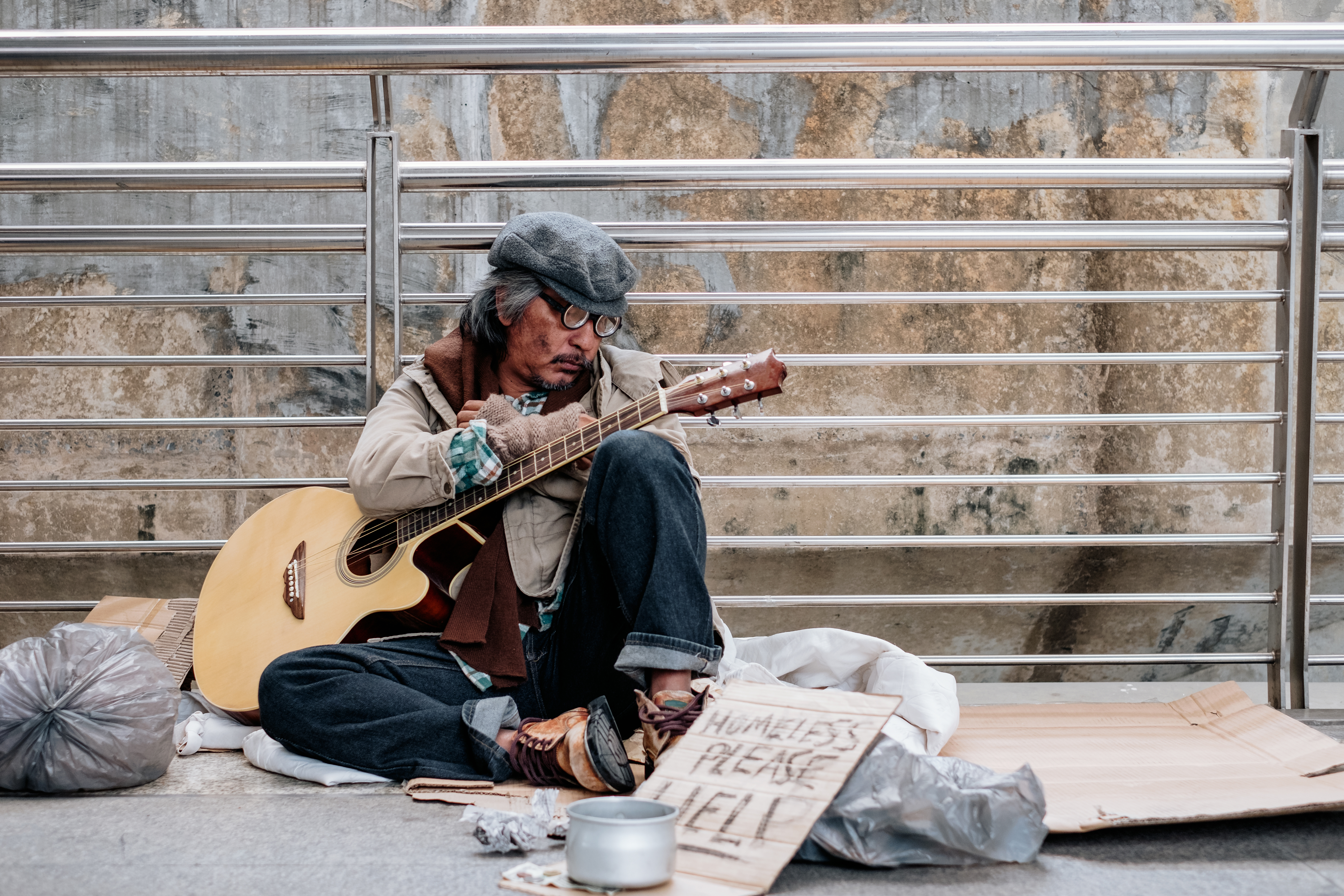 Homeless person sit holding guitar. | Source: Shutterstock