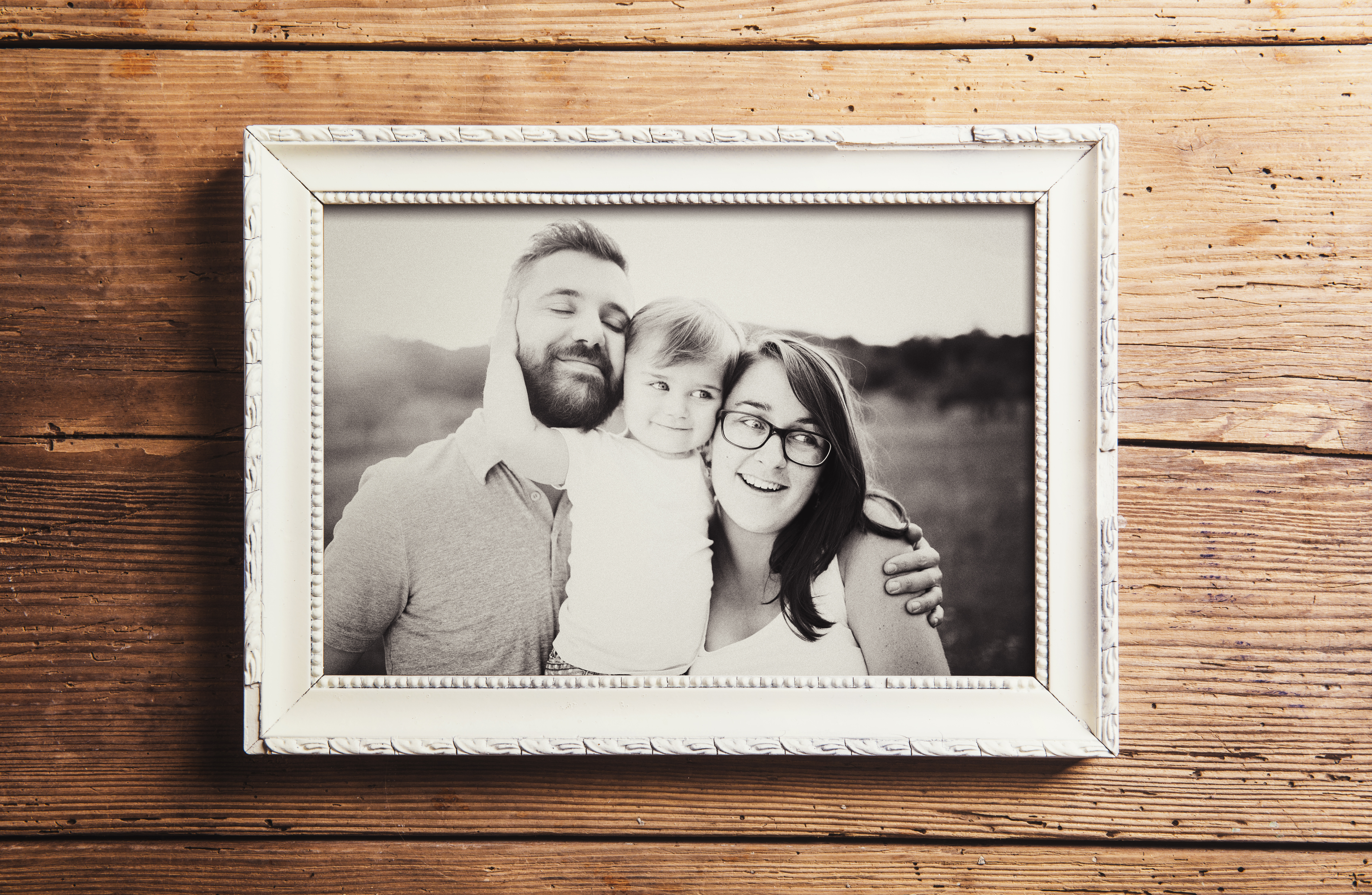A grayscale photograph of a family of three in a wooden frame | Source: Shutterstock